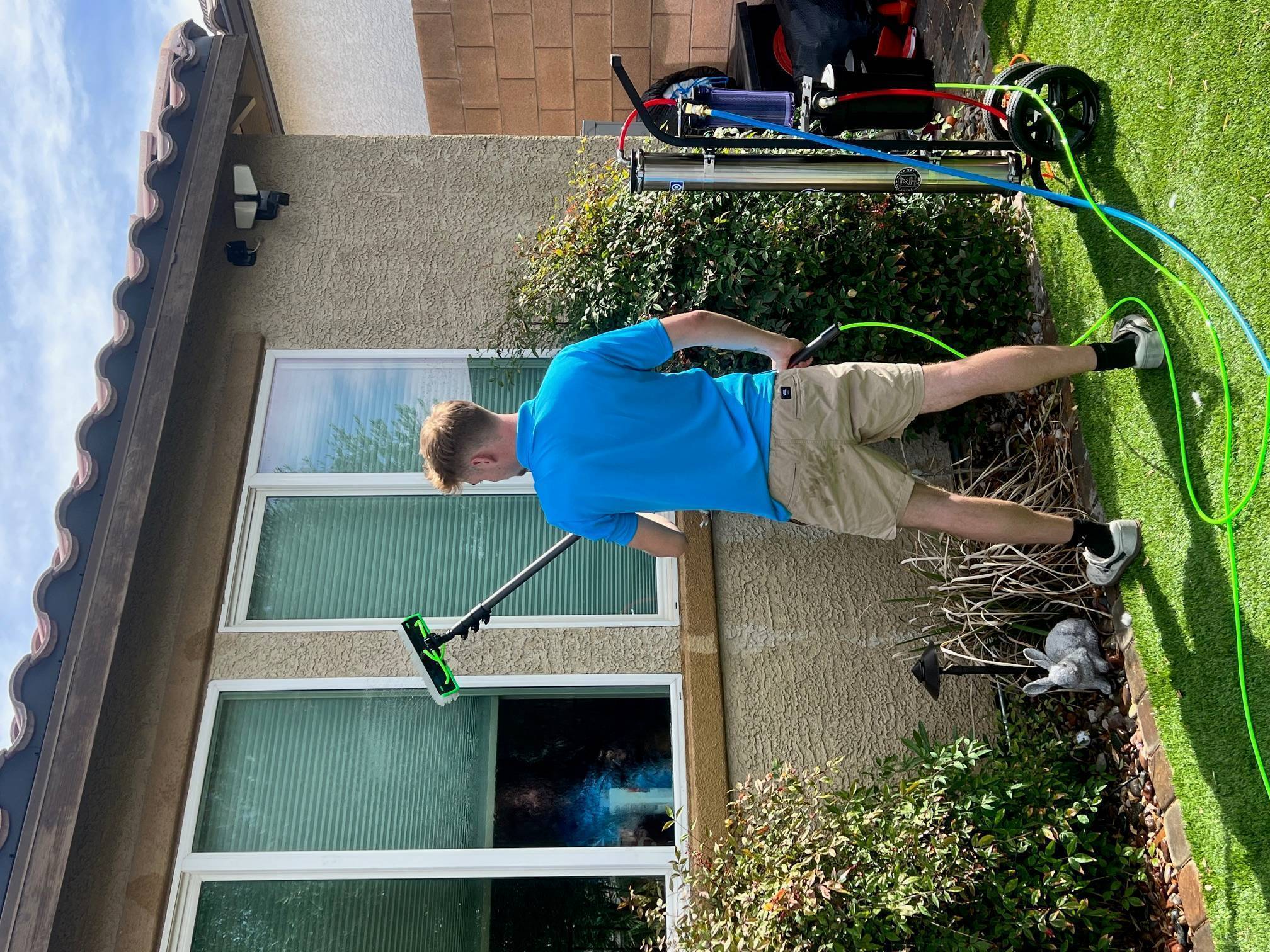 Professional window cleaner using extension pole to clean second-story window in Las Vegas Professional window cleaner using extension pole to clean second-story window in Las Vegas