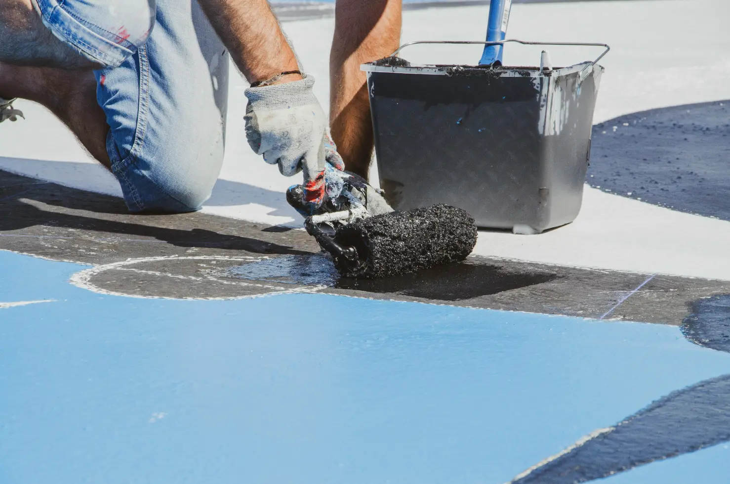 sample photo of a man painting using rollers with black paint