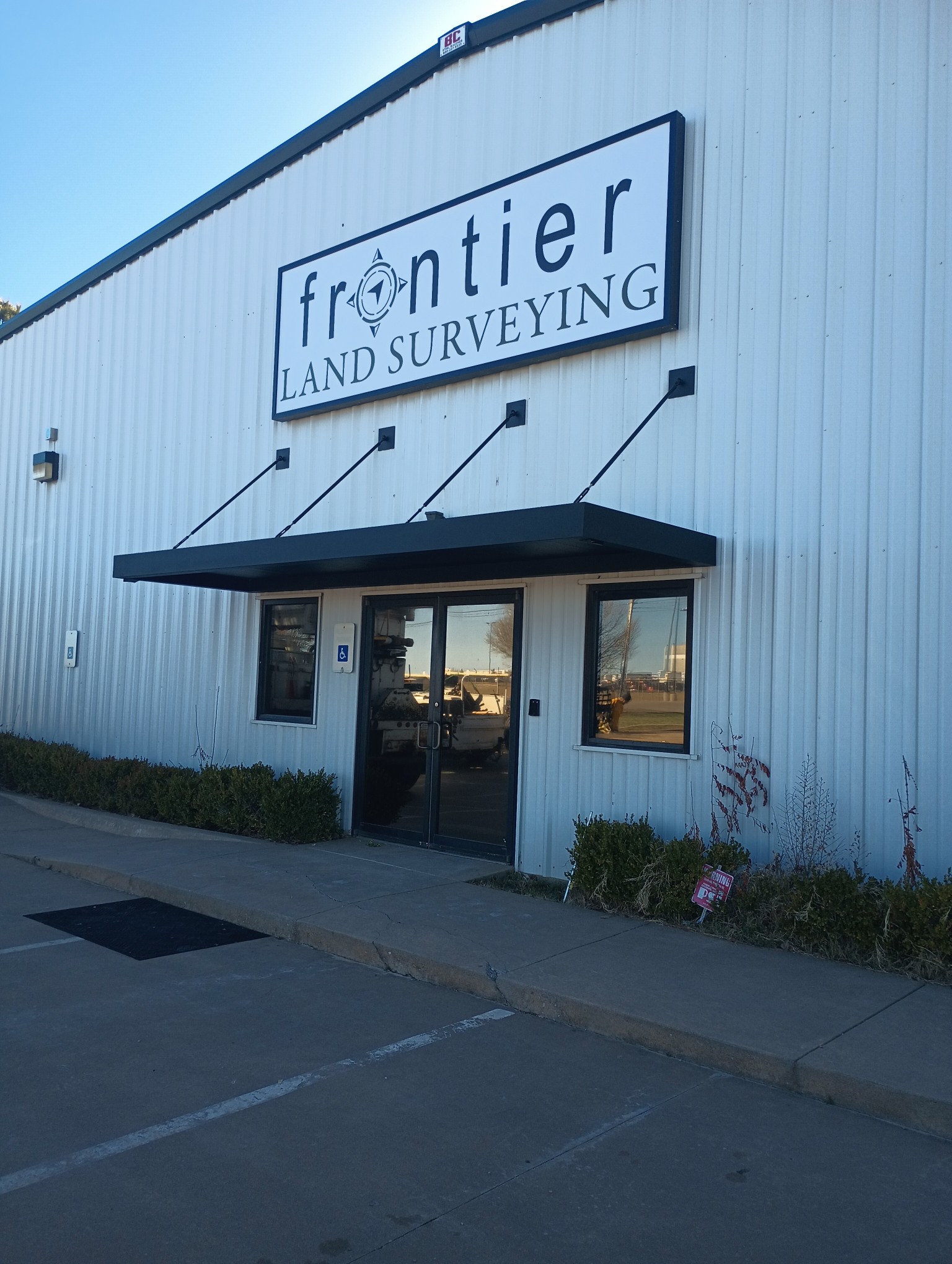 Commercial metal canopy installed above the entrance of Frontier Land Surveying office building.