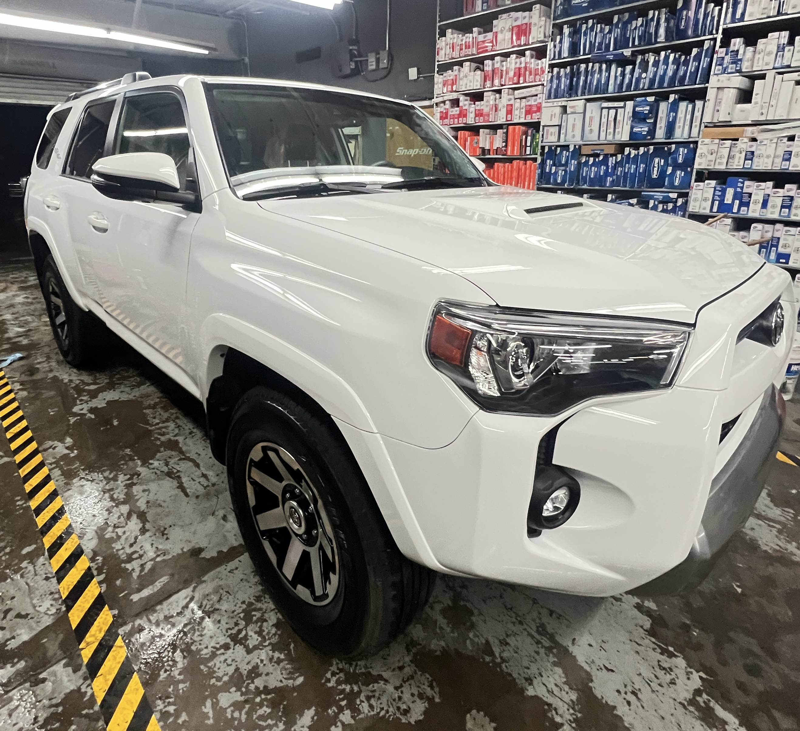 A Toyota 4Runner undergoing a professional detailing service. The interior is protected with plastic coverings on the seats, steering wheel, and floor, showcasing a clean and meticulous process. The well-organized detailing shop is visible in the background." A Toyota 4Runner undergoing a professional detailing service. The interior is protected with plastic coverings on the seats, steering wheel, and floor, showcasing a clean and meticulous process. The well-organized detailing shop is visible in the background."