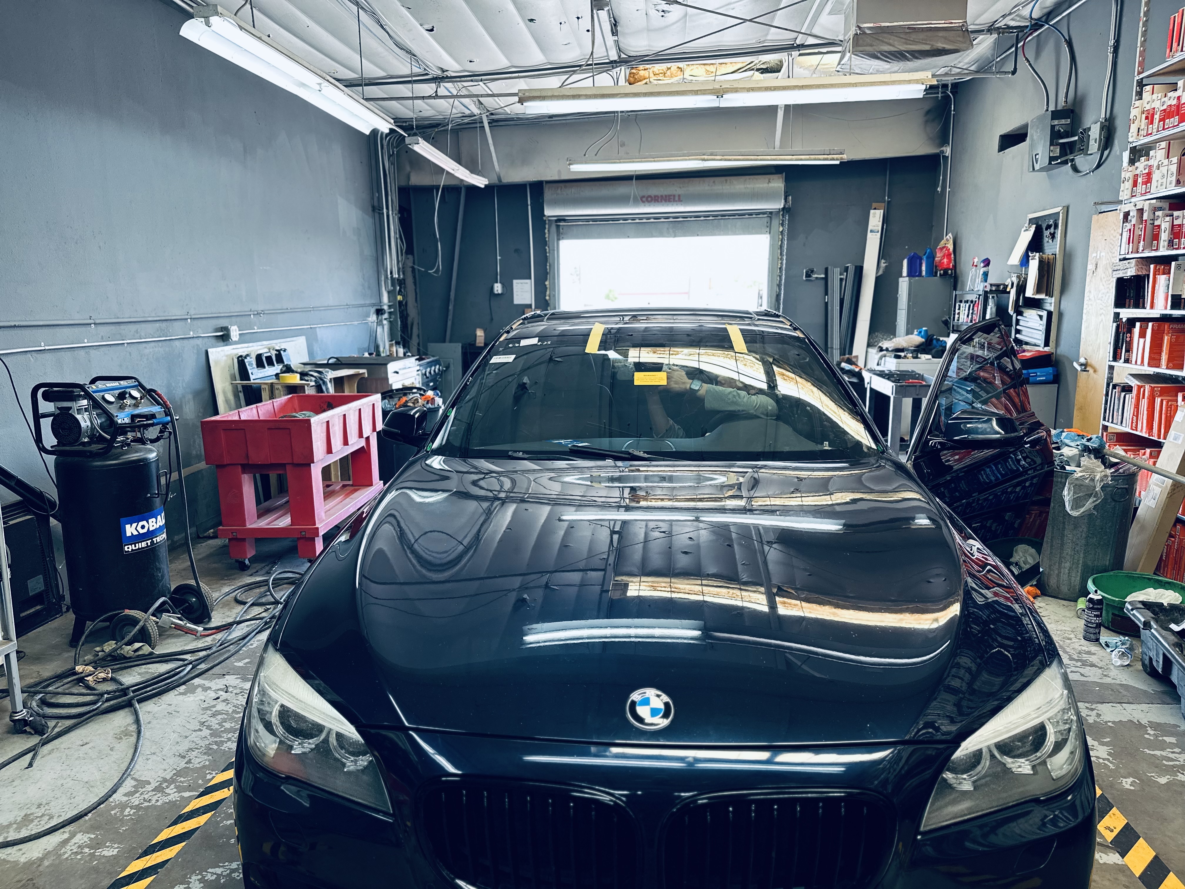 “Technician at Donny’s Automotive working on the front wheel bearing of a BMW 7 Series in the repair bay.” “Technician at Donny’s Automotive working on the front wheel bearing of a BMW 7 Series in the repair bay.”