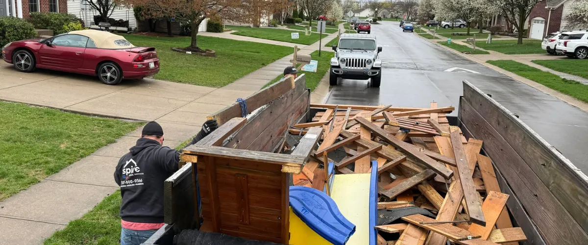 Residential street scene with a cleanup crew loading construction debris and household junk onto a trailer during a home cleanout. Residential street scene with a cleanup crew loading construction debris and household junk onto a trailer during a home cleanout.
