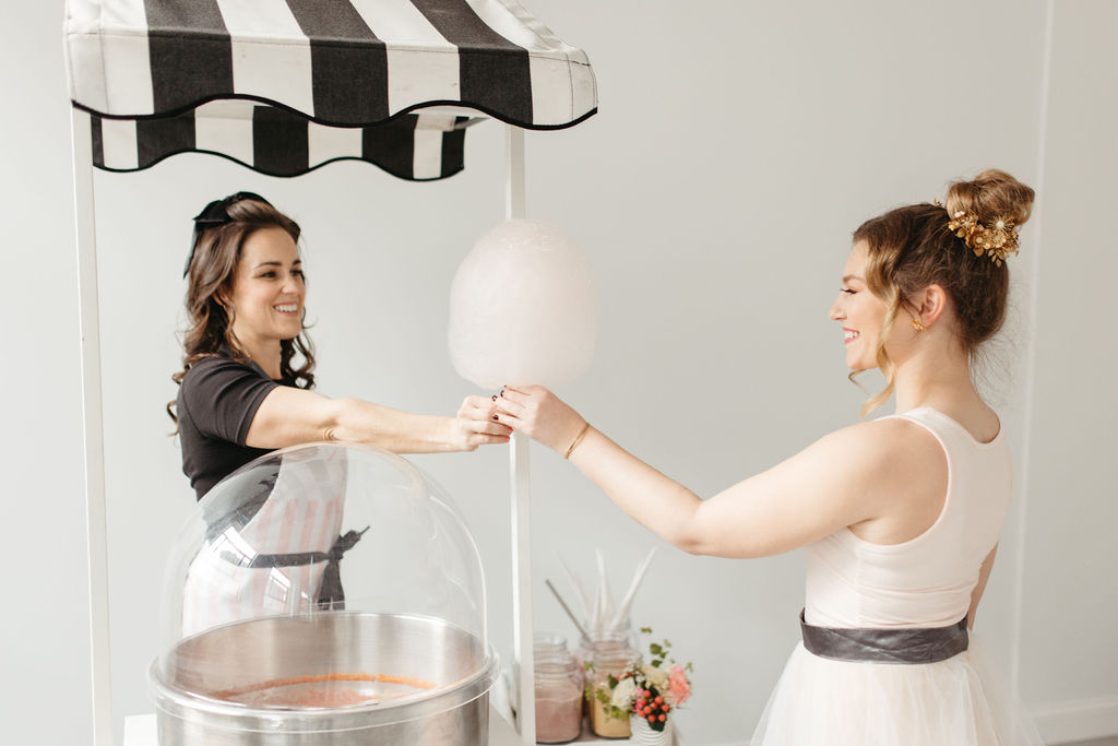 woman handing cotton candy to another woman and smiling