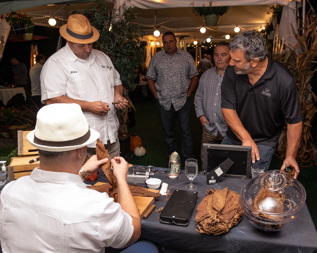 men making cigars at table at event