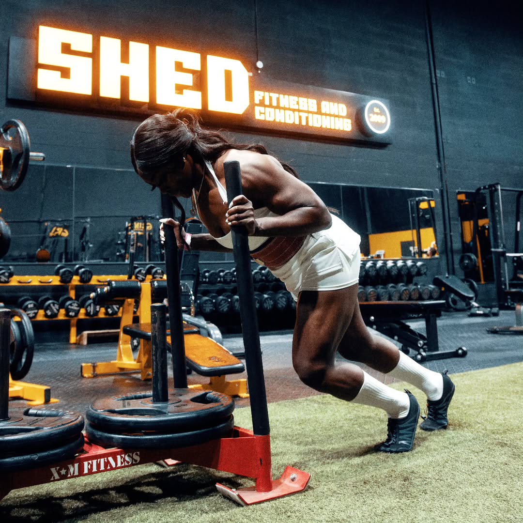 Shed Fitness athlete pushing a sled on the turf