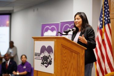 A woman in a black blazer standing at a podium.