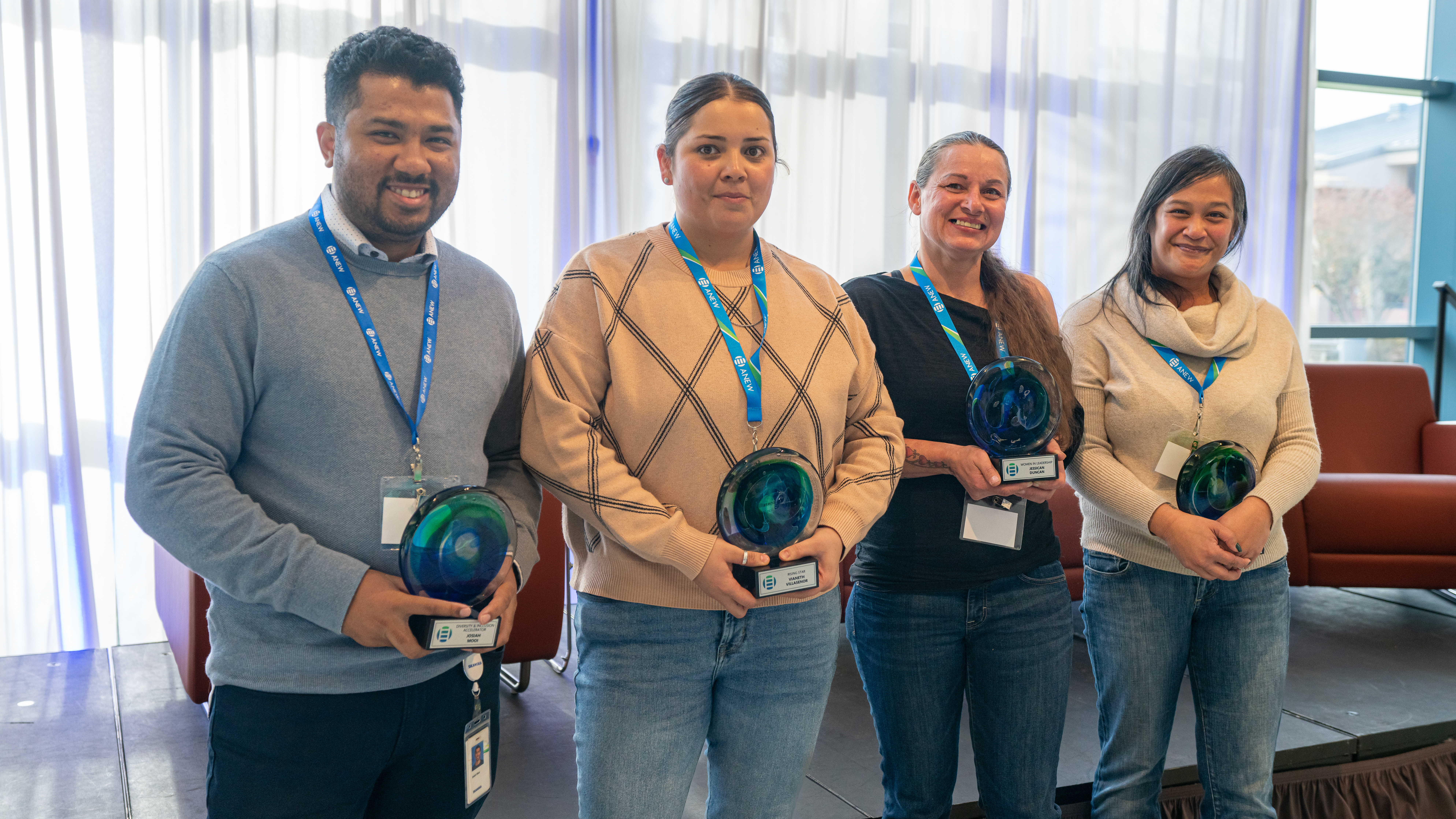 Four people standing in a line holding awards.