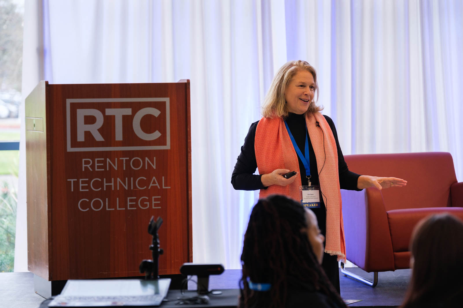 A women in a coral scarf on stage.