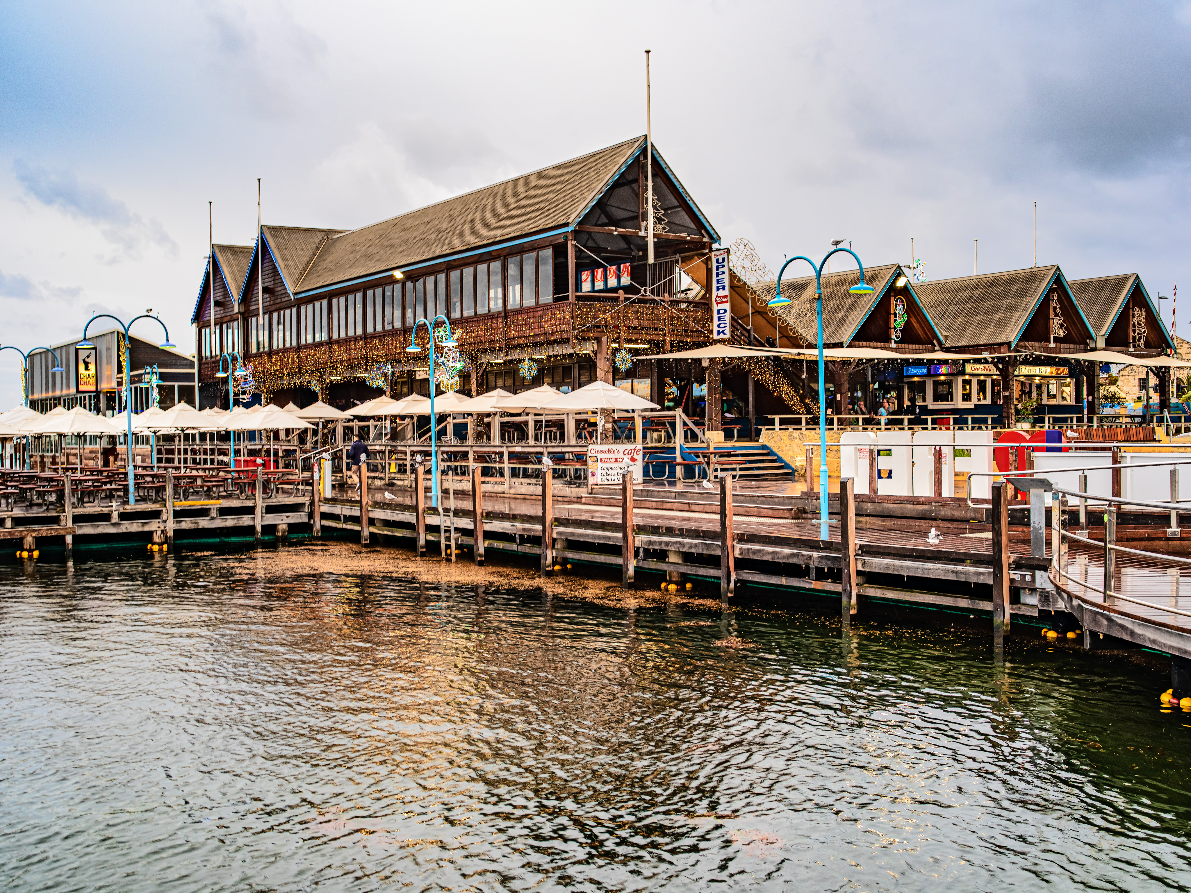 Waterfront boardwalk at Hillarys Boat Harbour with restaurants and patios over the water in Perth