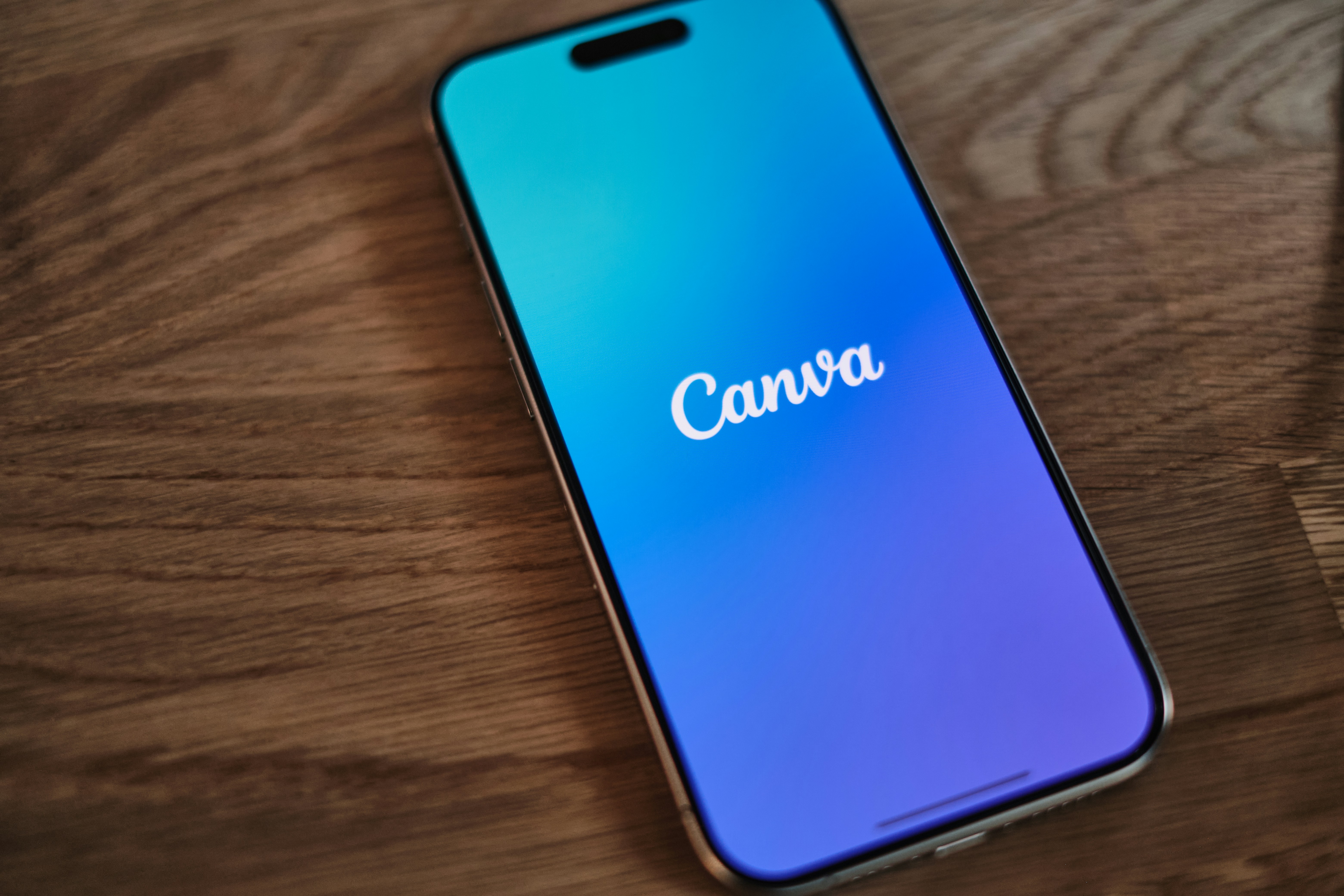 Call Phone laying on a table with blue screen with canva logo Call Phone laying on a table with blue screen with canva logo