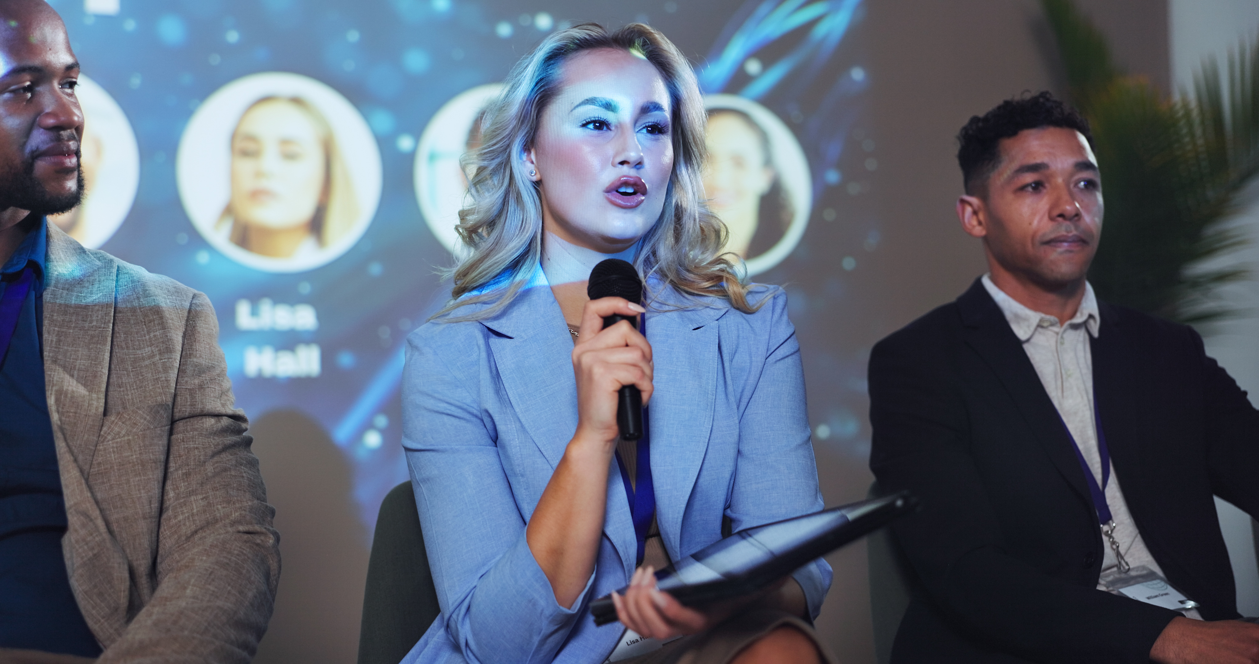 Woman holding mic and speaking at conference.