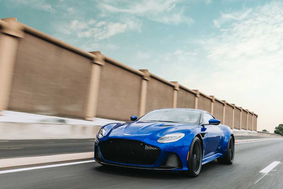 Blue coupe driving on open road under clear sky, representing vehicle ownership updates and how to fix a written mistake on a car title when selling.