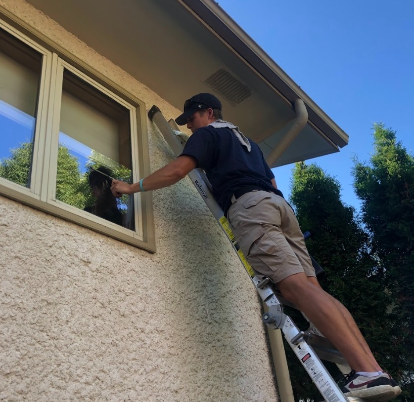 Christian hard at work cleaning a second story window.