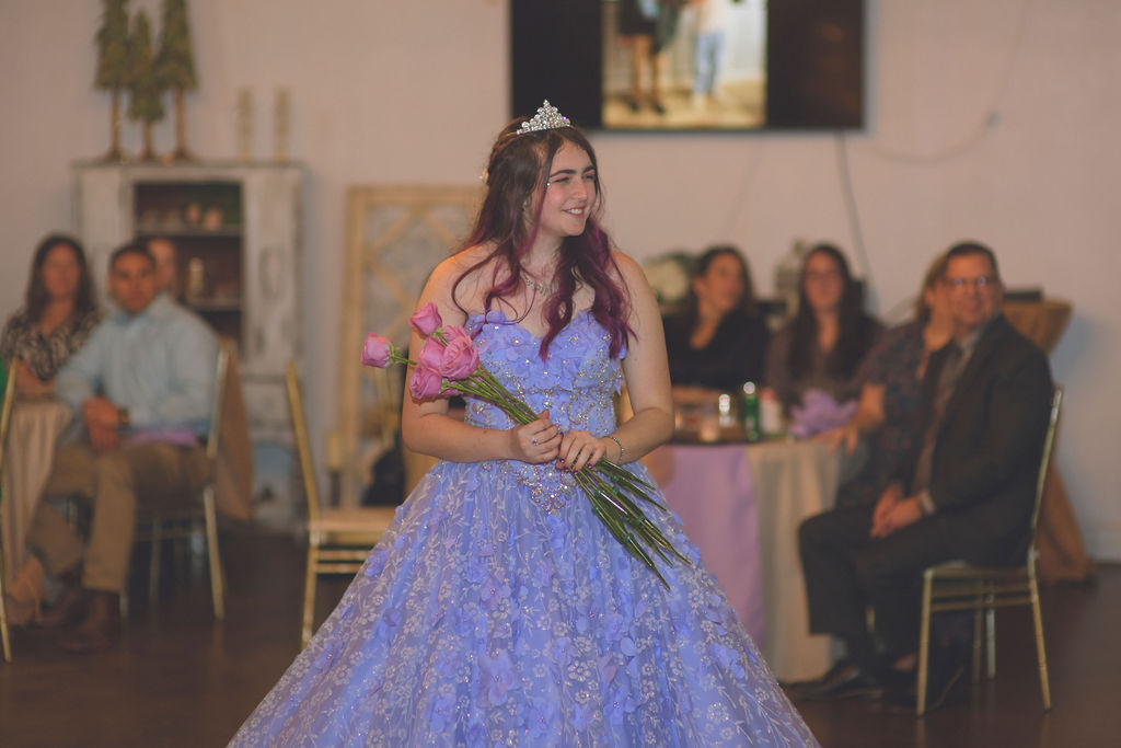 Iliana during her Alice in Wonderland quinceanera holding roses, dressed in a beautiful light purple quinceanera dress, capturing a special moment of her Alice in Wonderland quince theme.