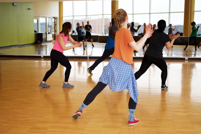 A group of people practicing dance routines in a mirrored studio. The dancers are in mid-movement, focusing on coordination and timing, highlighting the importance of rehearsing to avoid a quinceañera dance disaster and ensure a flawless performance.