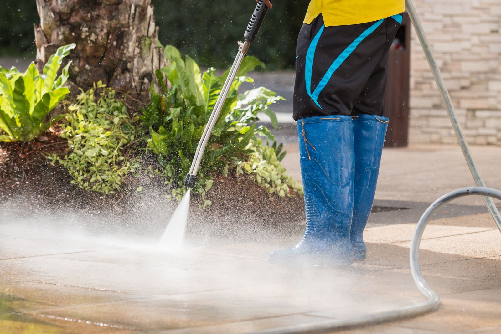 a person wearing blue boots and holding a pressure washer