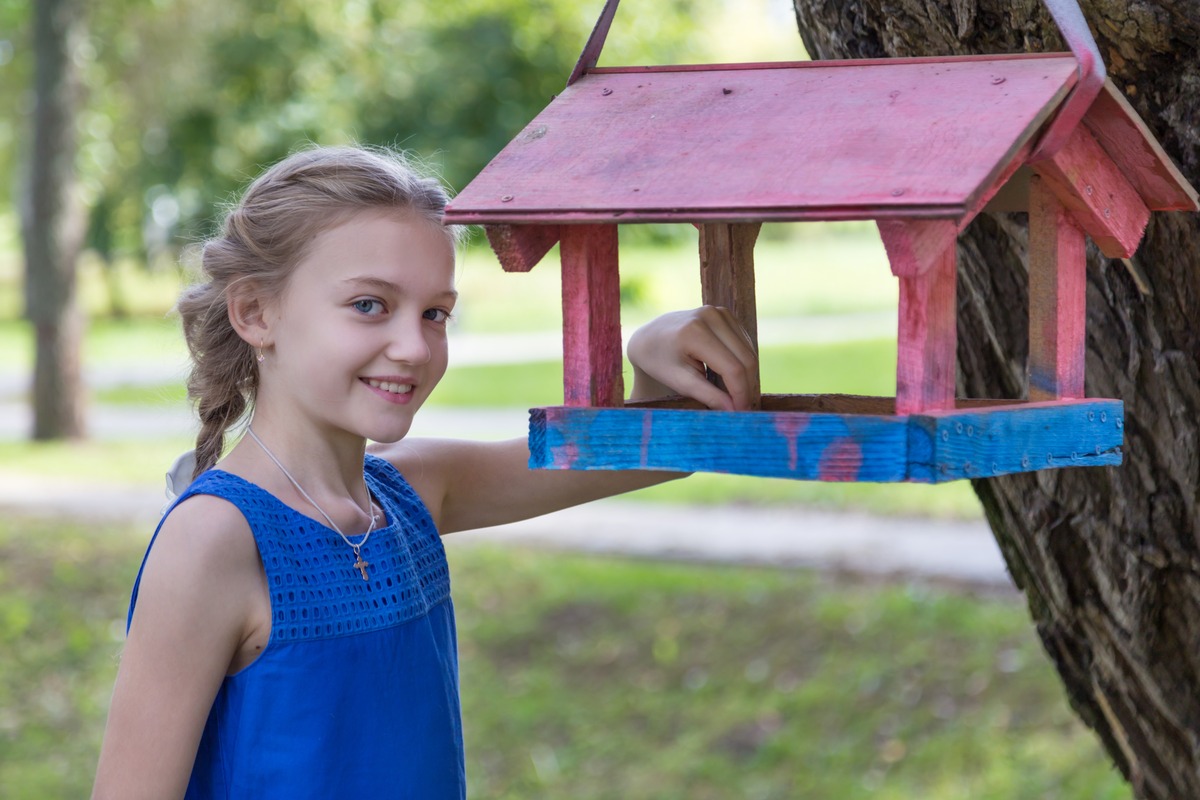 girl outdoors during summer near birdhouse