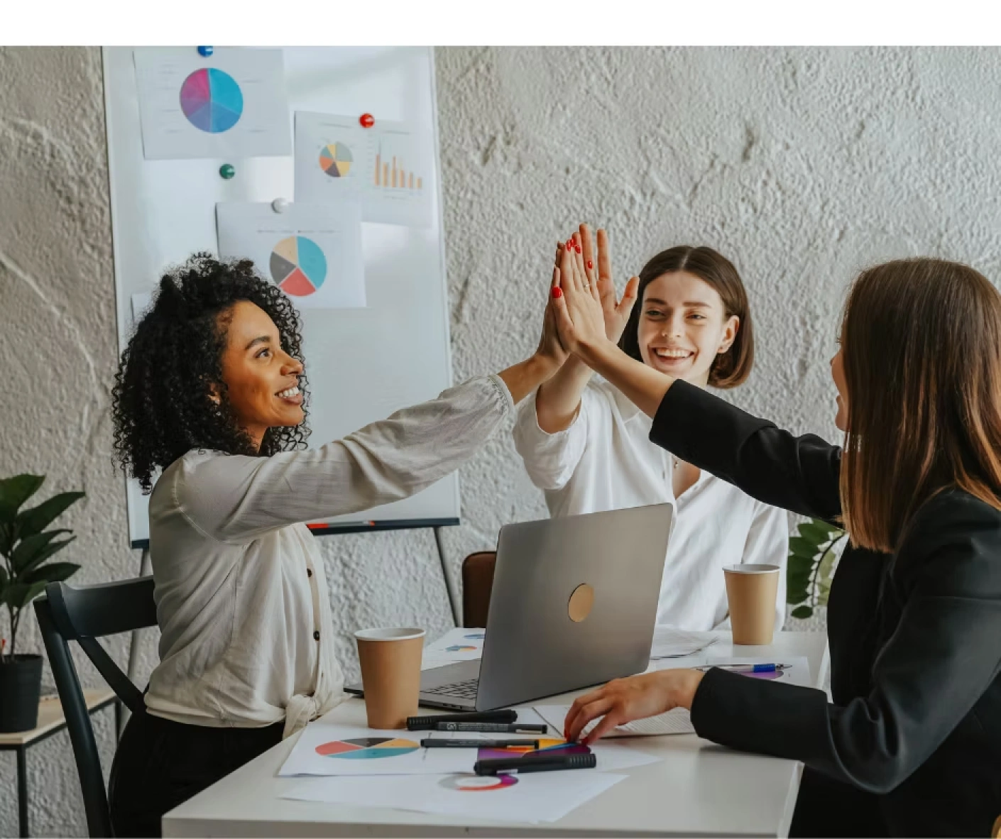 Women business leaders celebrating success with a high-five during a tax strategy planning session.