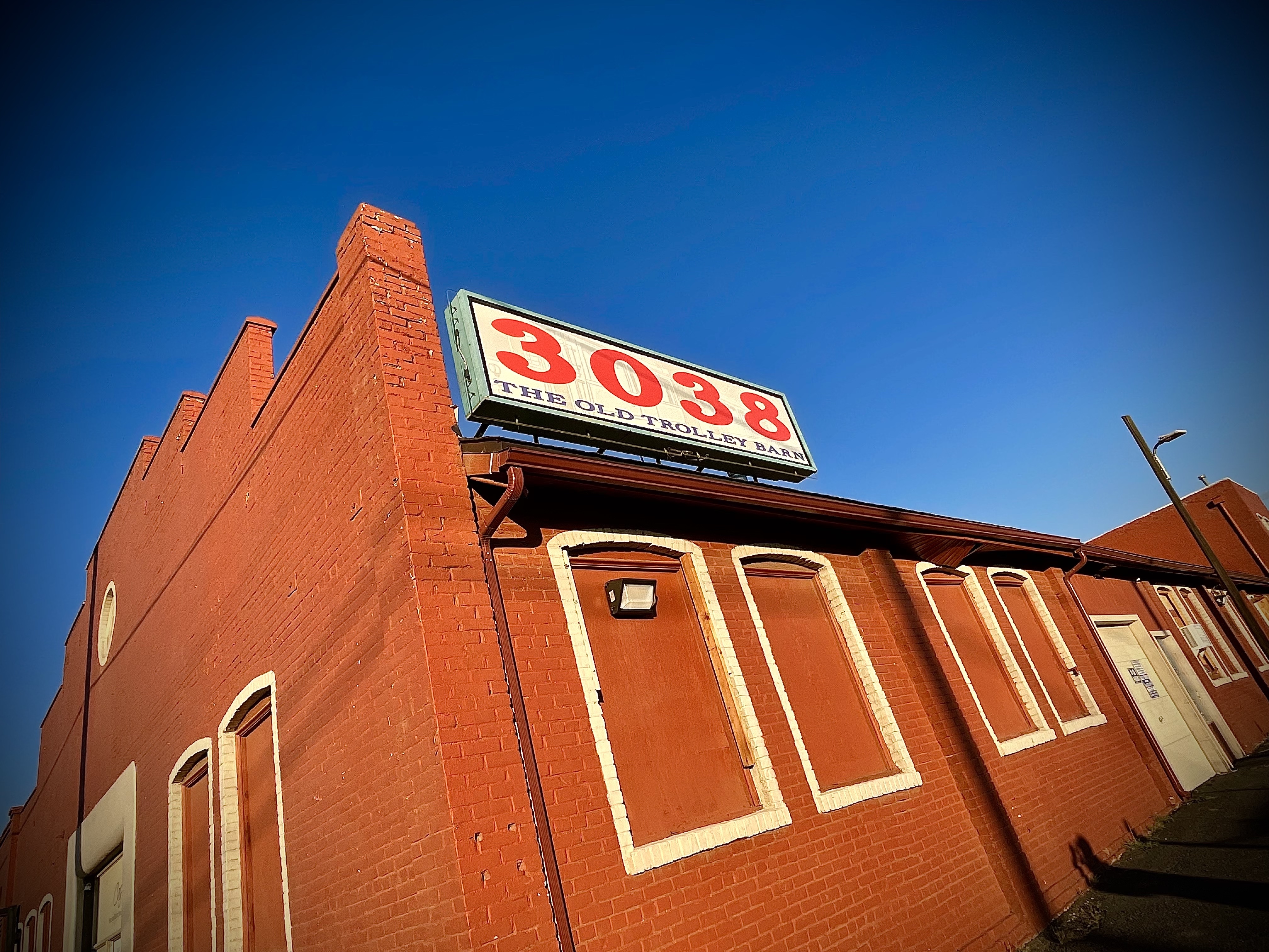 A panoramic view of the Old Trolley Barn in Spokane, showcasing its distinctive red brick architecture against a bright blue sky with fluffy clouds. The building features multiple arched windows and is surrounded by remnants of construction, highlighting its historic and urban character. A panoramic view of the Old Trolley Barn in Spokane, showcasing its distinctive red brick architecture against a bright blue sky with fluffy clouds. The building features multiple arched windows and is surrounded by remnants of construction, highlighting its historic and urban character.
