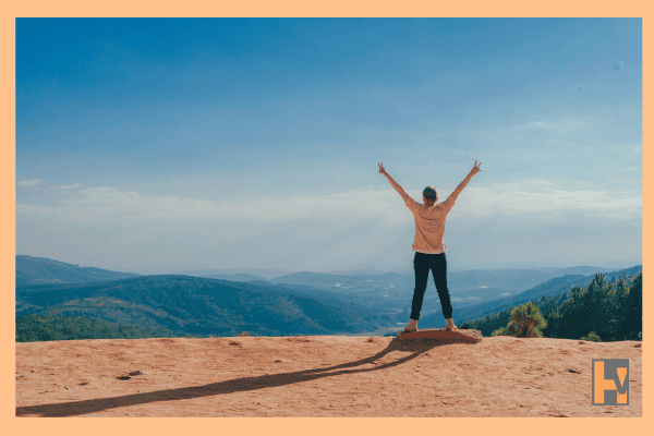 perosn on mountain peak with arms raised perosn on mountain peak with arms raised