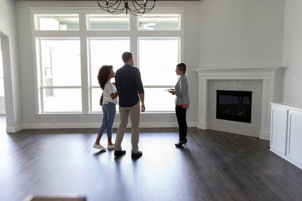 Couple touring a home with a real estate agent in a bright, modern living room Couple touring a home with a real estate agent in a bright, modern living room