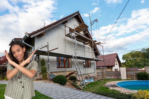 Smiling woman crossing arms in front of a house under construction Smiling woman crossing arms in front of a house under construction