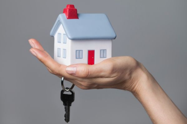 Hand holding miniature house with key Hand holding miniature house with key