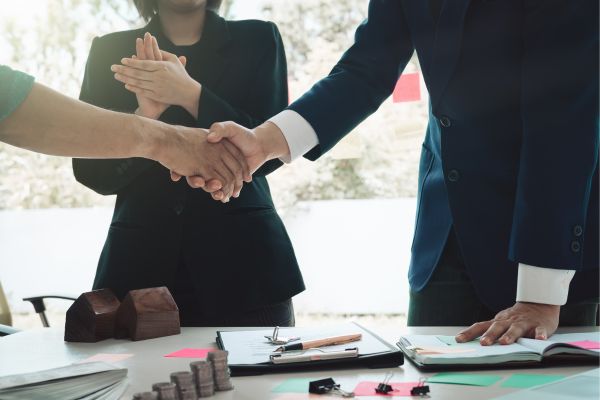 Businesspeople shaking hands over a signed real estate agreement Businesspeople shaking hands over a signed real estate agreement