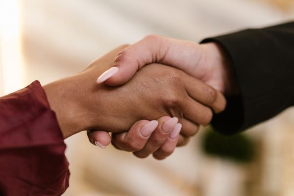 Close-up of a handshake between two women in business attire. Close-up of a handshake between two women in business attire.
