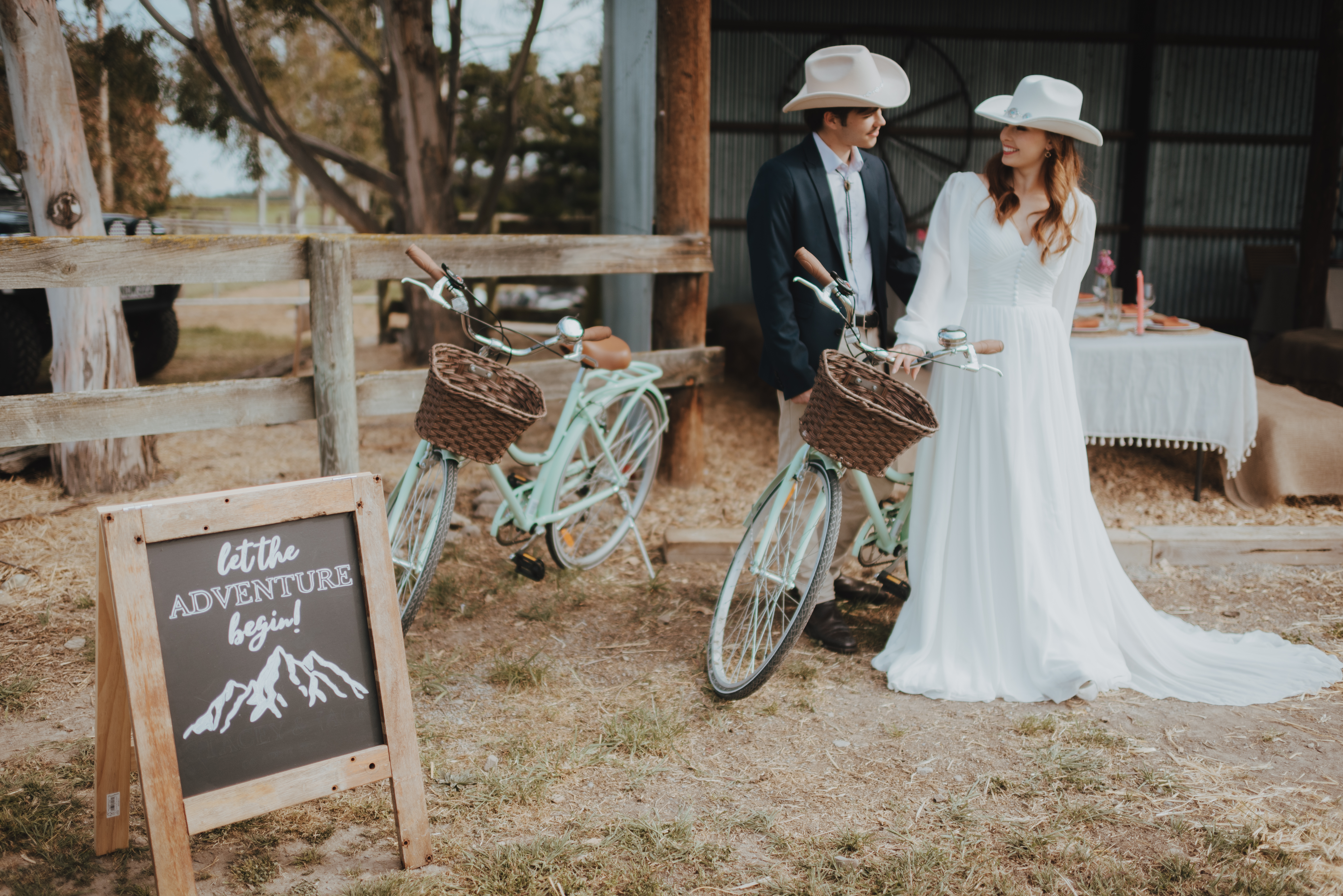 couple standing next to rustic barn and bike for wedding photos