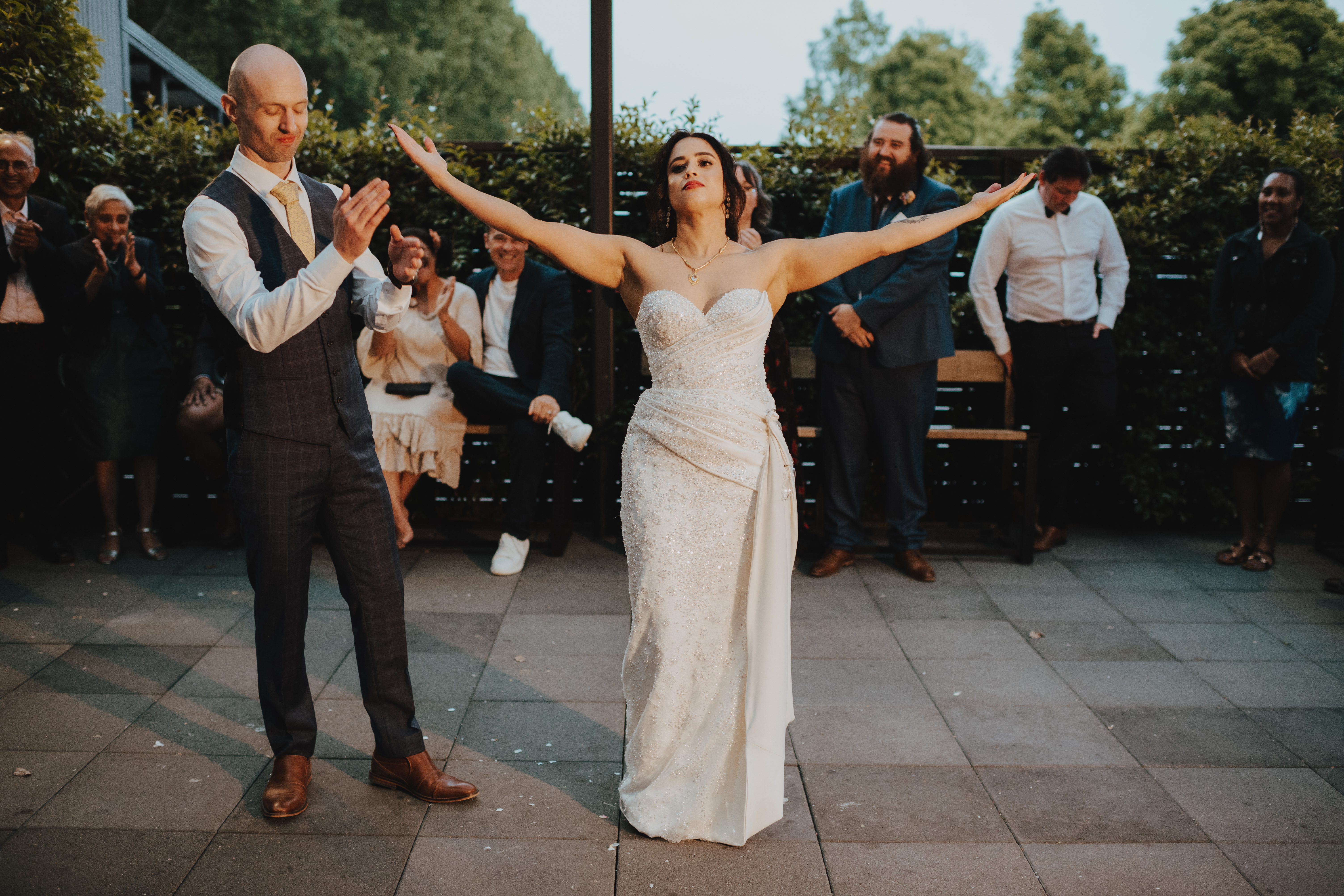 bride taking a bow while her groom claps after the first dance