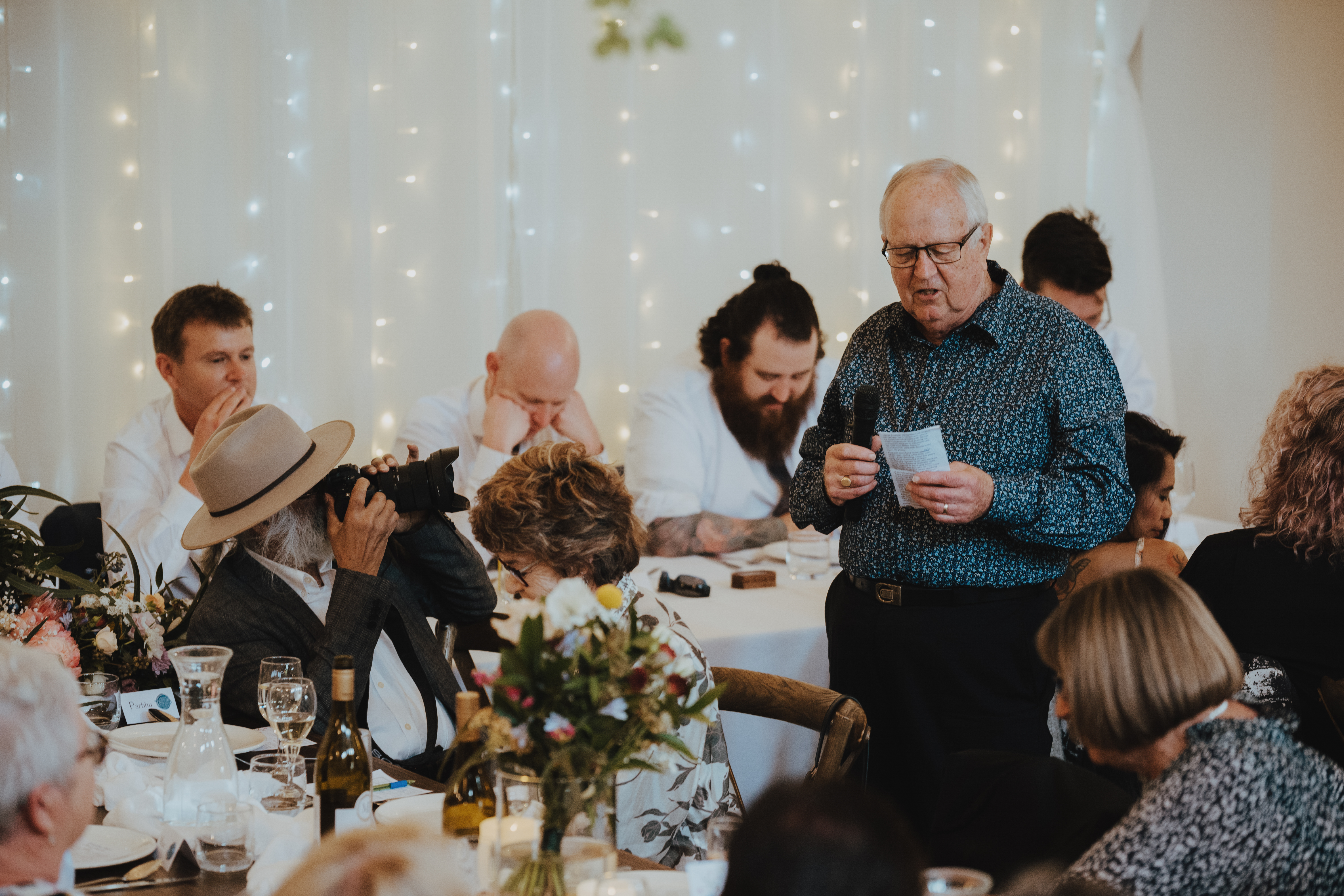 grooms father making his speech while the brides father takes photos