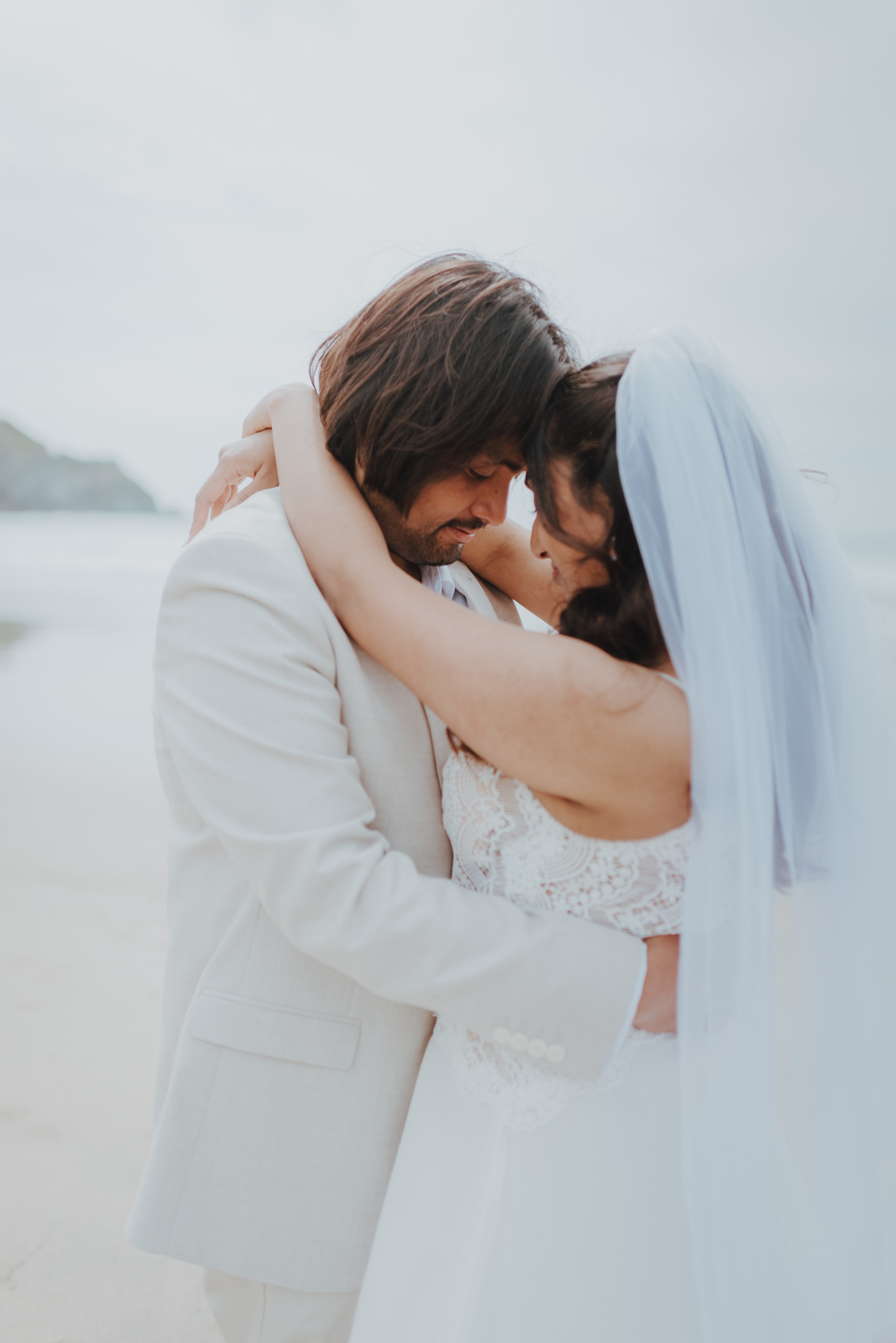 newlyweds leaning in for a kiss on the beach
