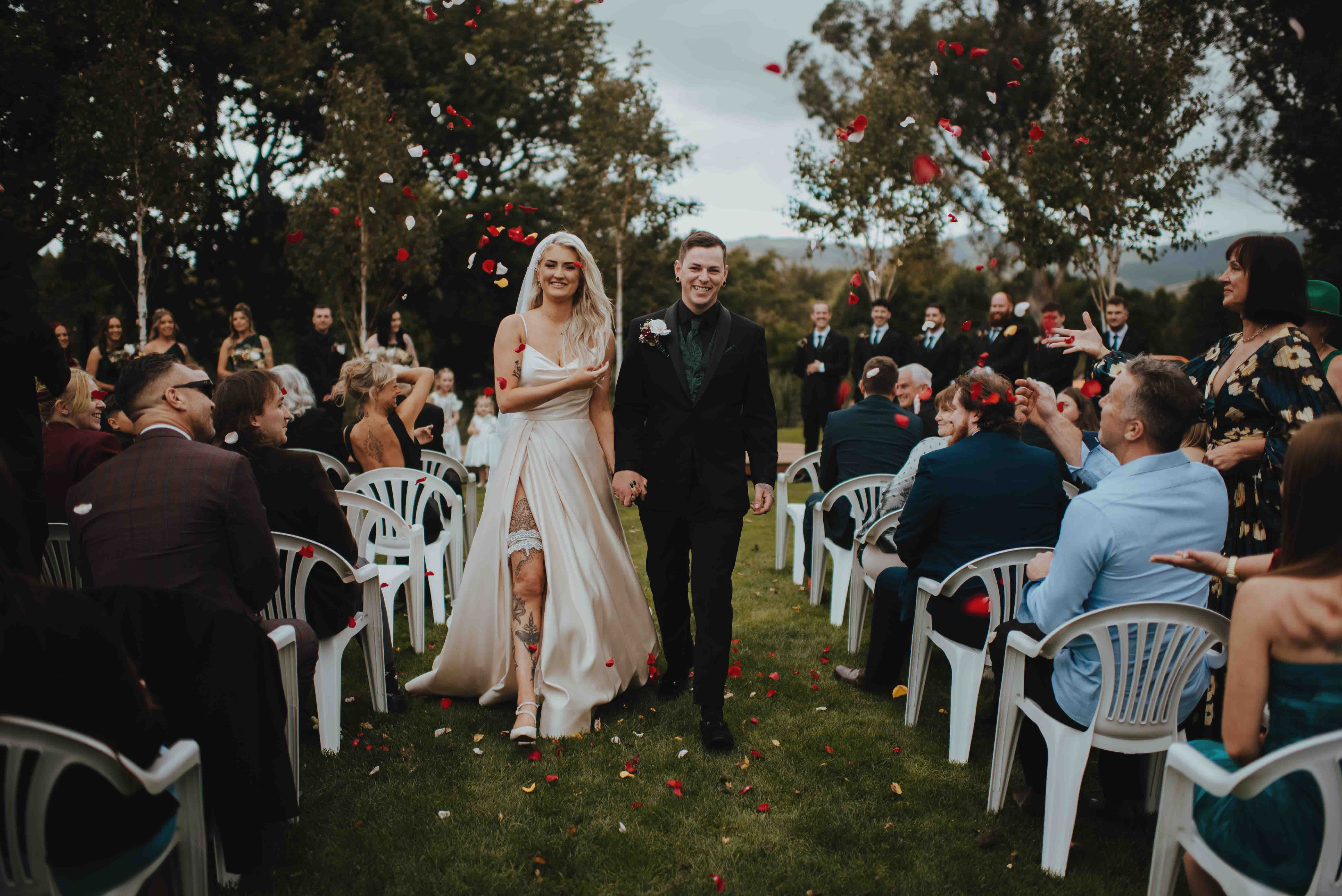 exiting the wedding ceremony surrounded by flying rose petals