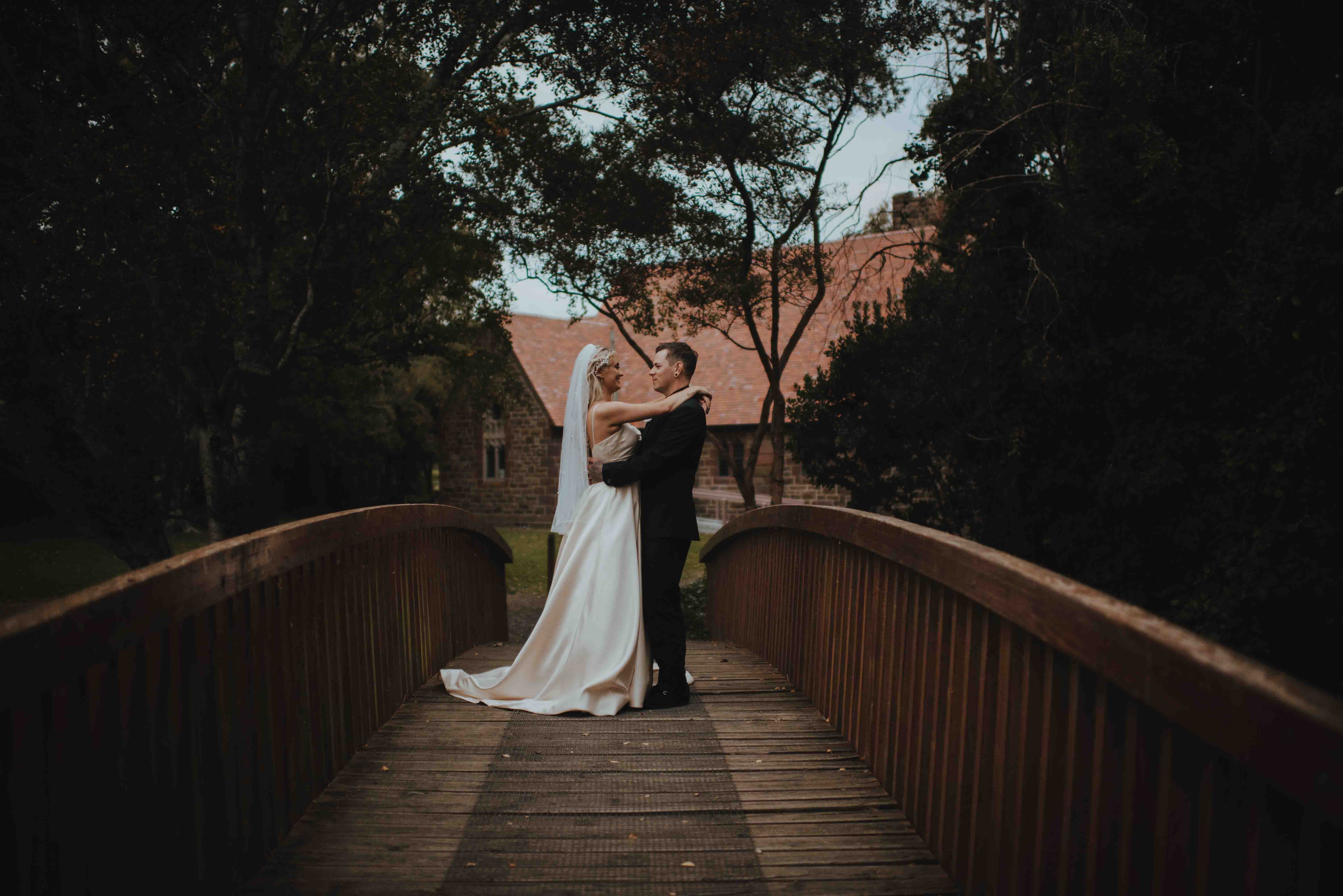 newlyweds sneaking away for pictures on a bridge near the tai tapu church