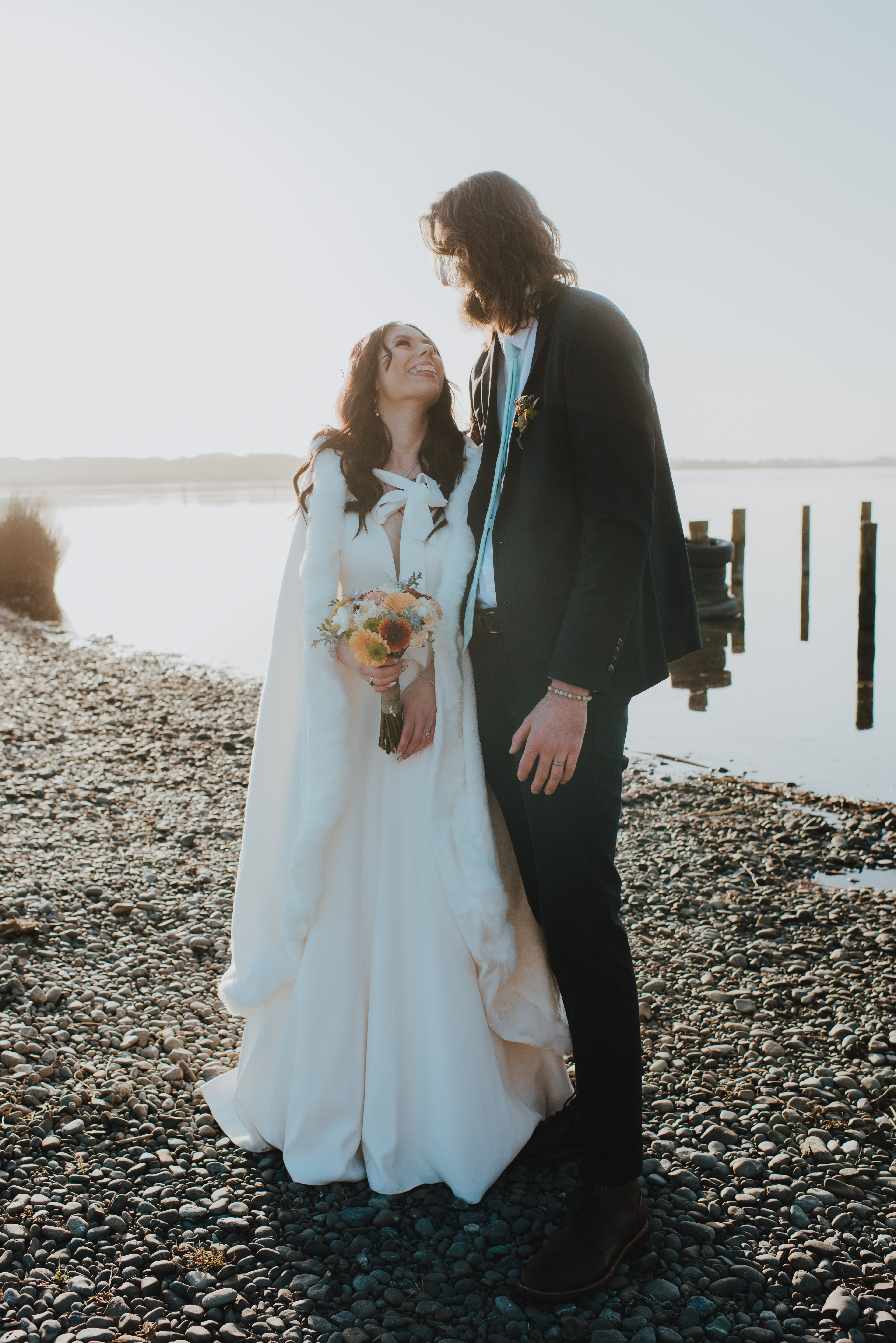 newlyweds standing by lakeside