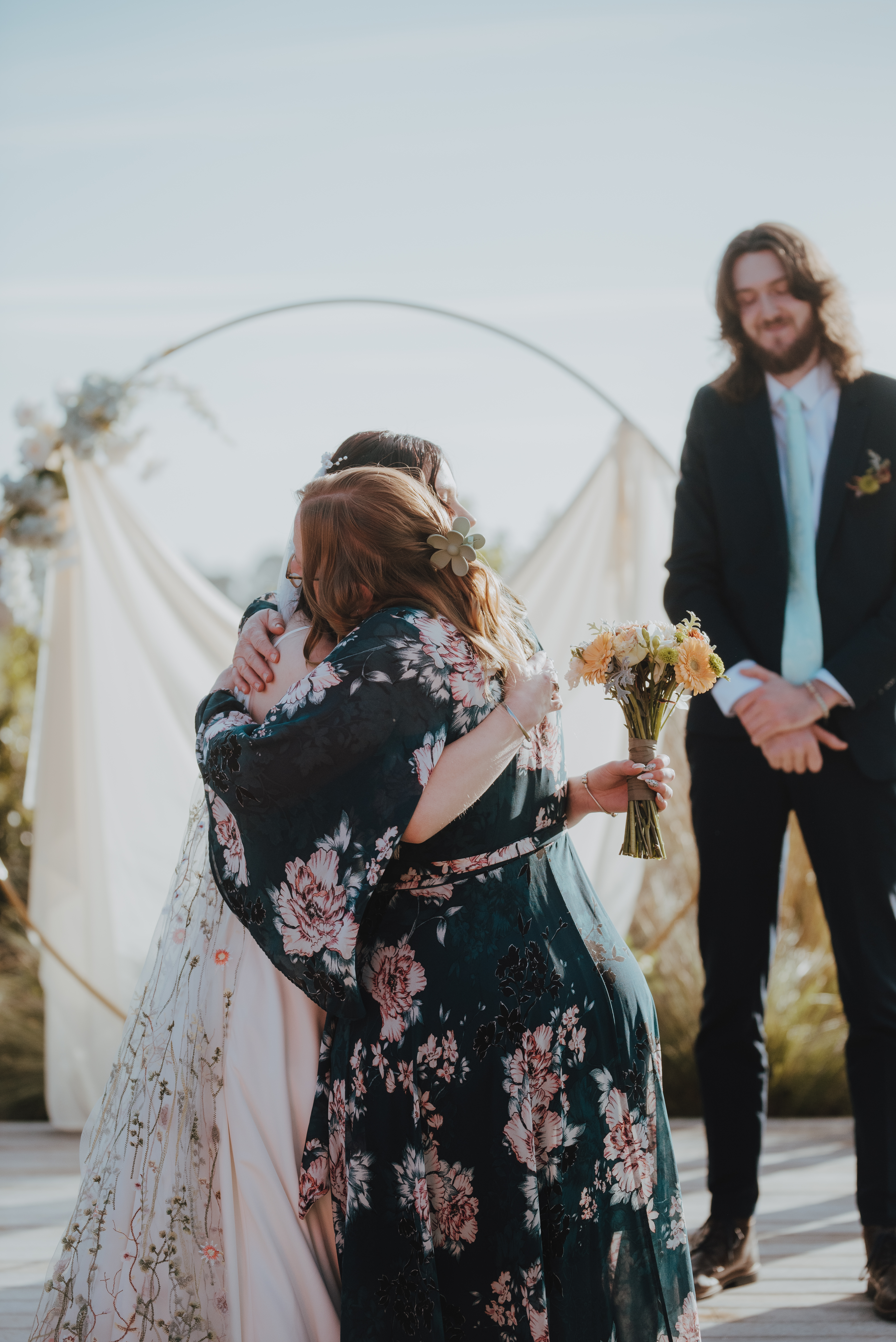 bride being hugged by woman giving her to her groom