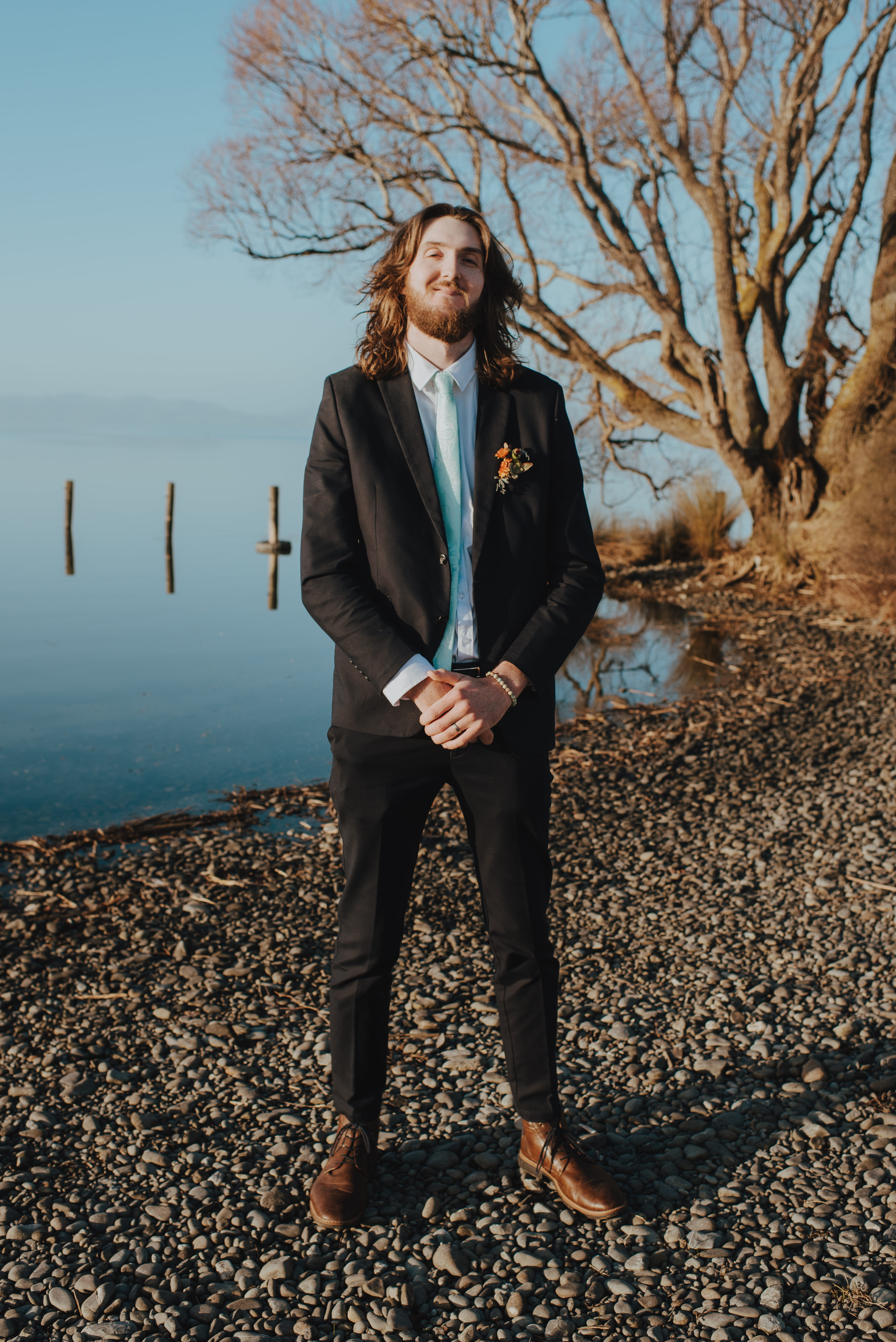 groom standing by lake edge