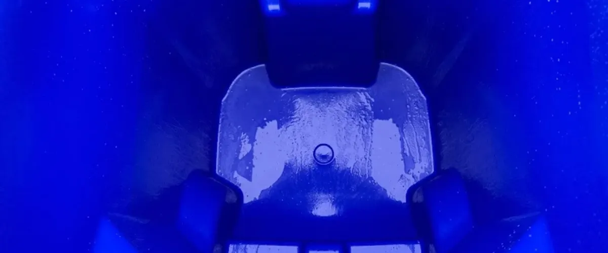 Brightly lit, freshly cleaned interior of a blue trash bin.