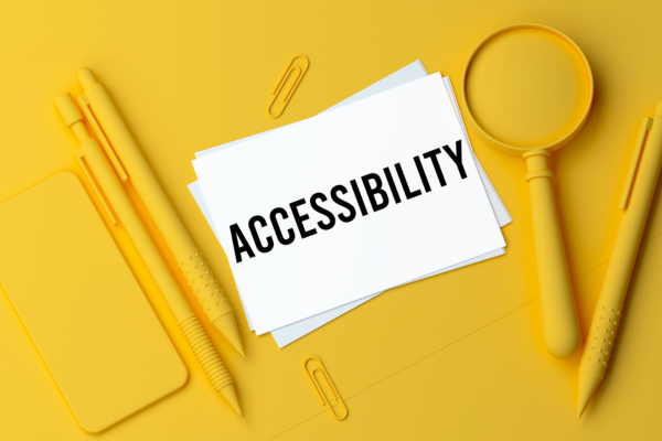 White paper image with the word "accessibility" written on it surrounded by a yellow monochromatic color scheme and objects