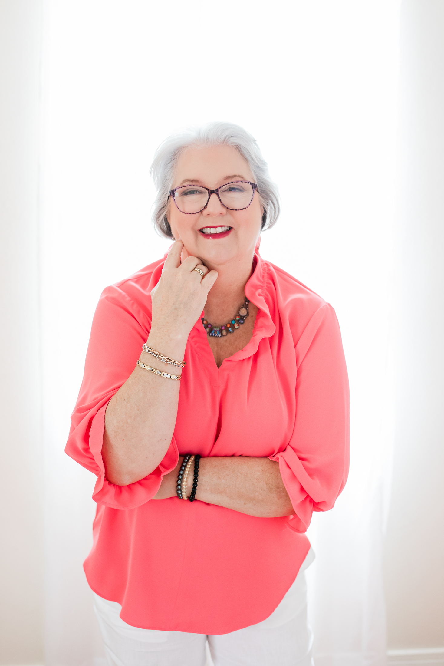 White woman over 60 with gray hair and wearing a pink top with professional hair and makeup styling doing a professional studio photo shoot in Houston TX with Amanda Faucett Photography