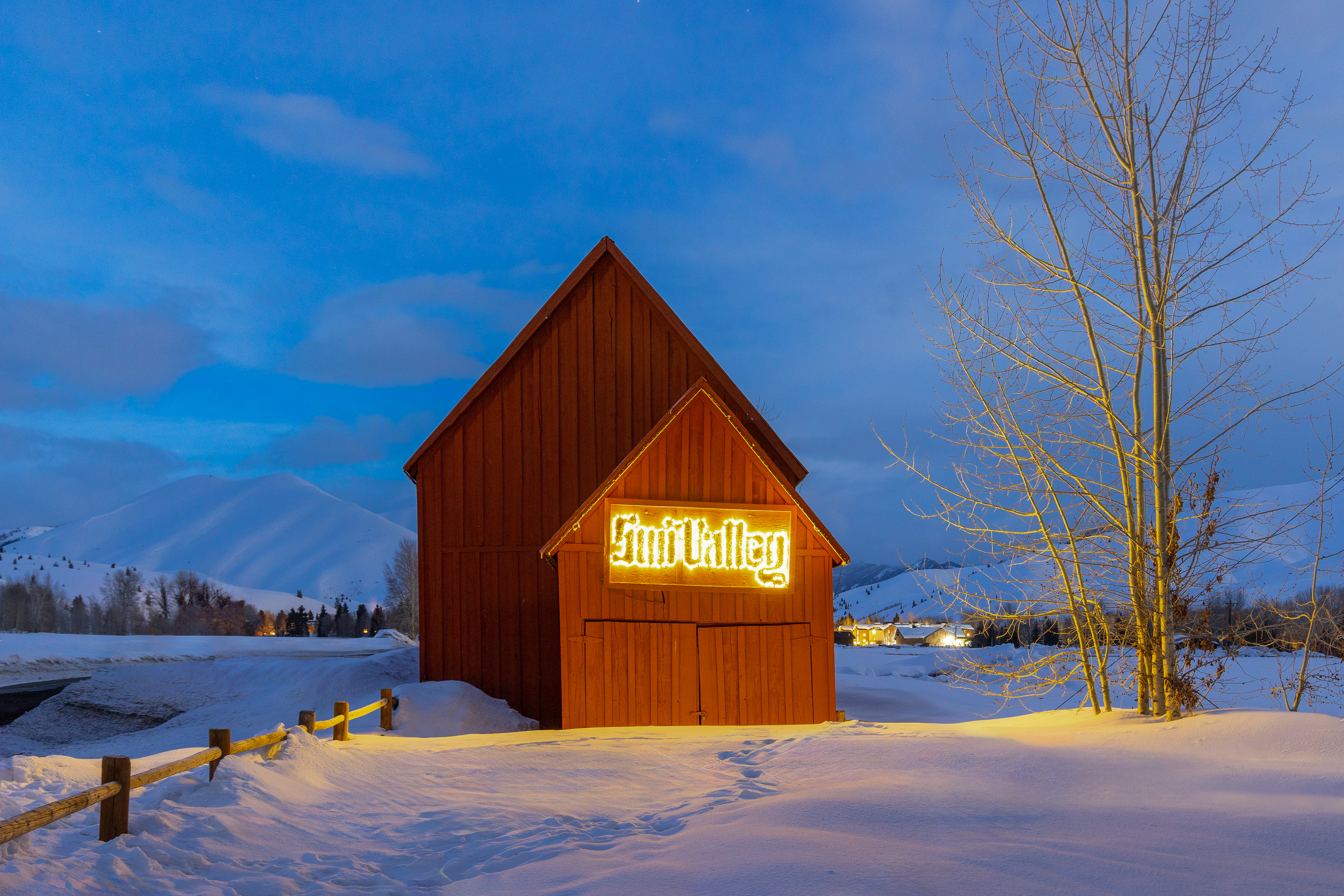 Sun Valley barn glowing at dusk with mountains in background
