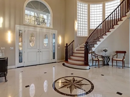 an elegant entryway remodeling with a grand staircase and intricate marble flooring.