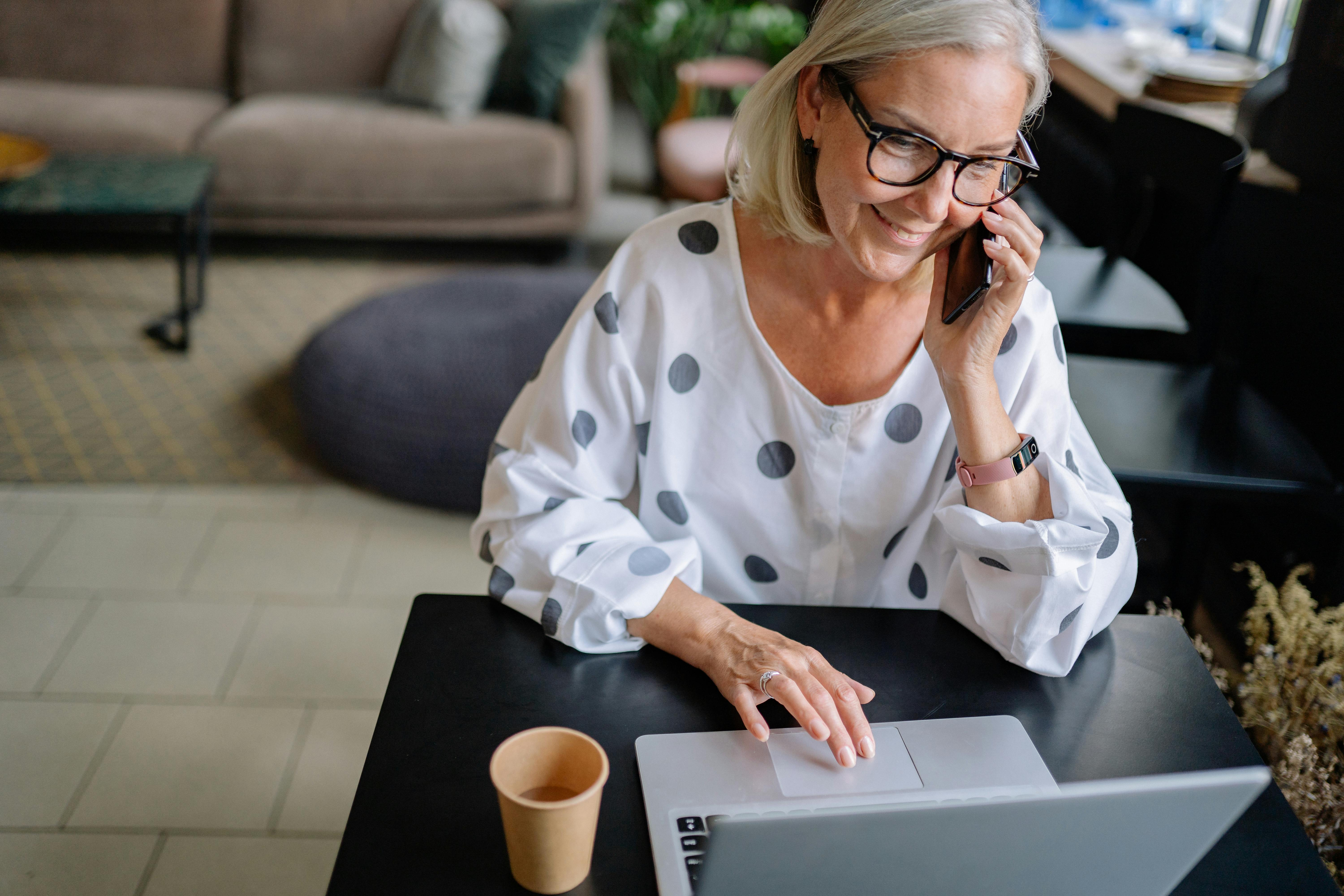 A senior nonprofit leader in New Orleans smiles while on the phone, successfully coordinating funding relief and managing operations on her laptop.