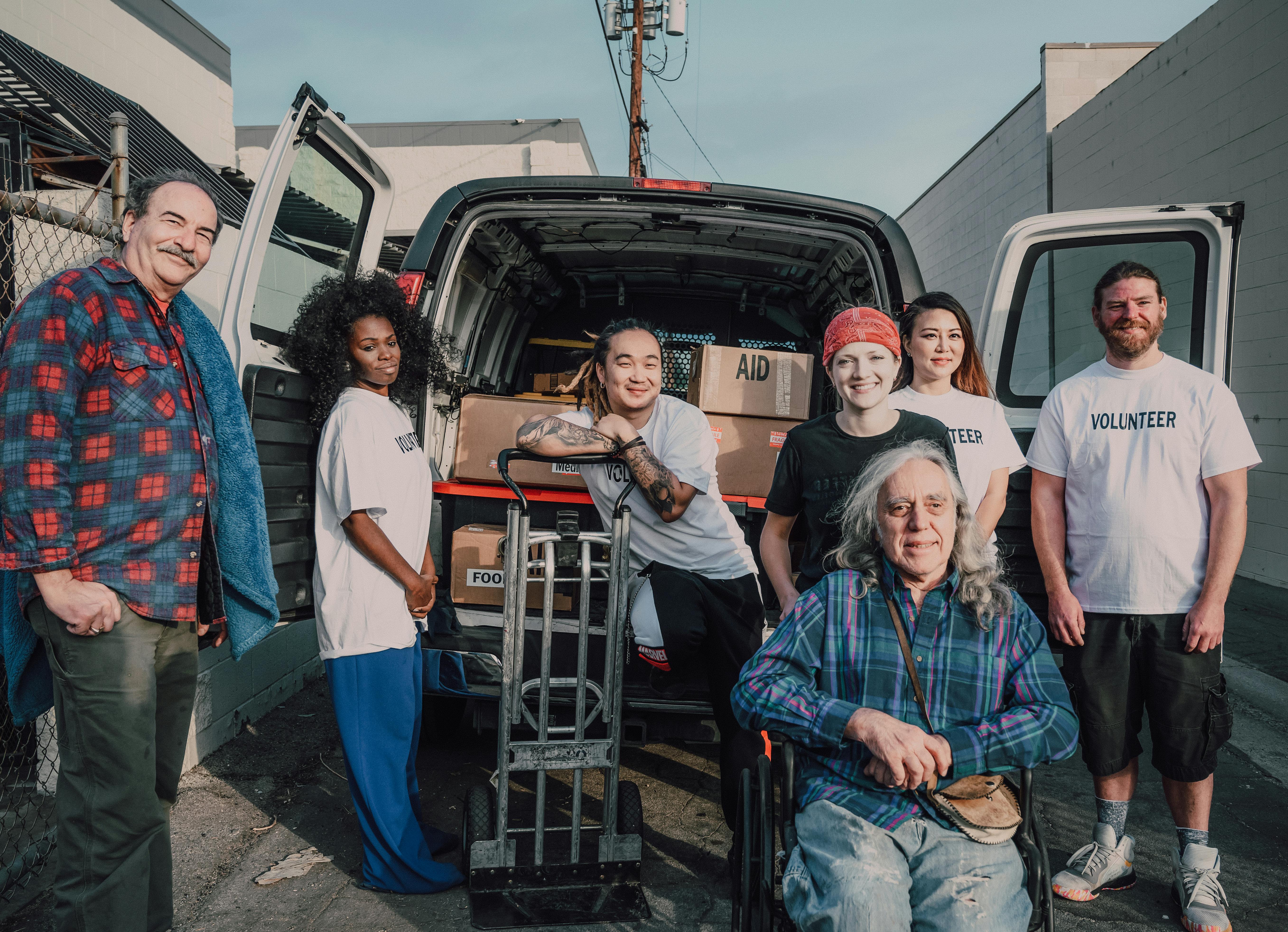 A group of dedicated NOLA volunteers of all ages stand proudly by a van full of aid, representing the community impact made possible by successful funding efforts.