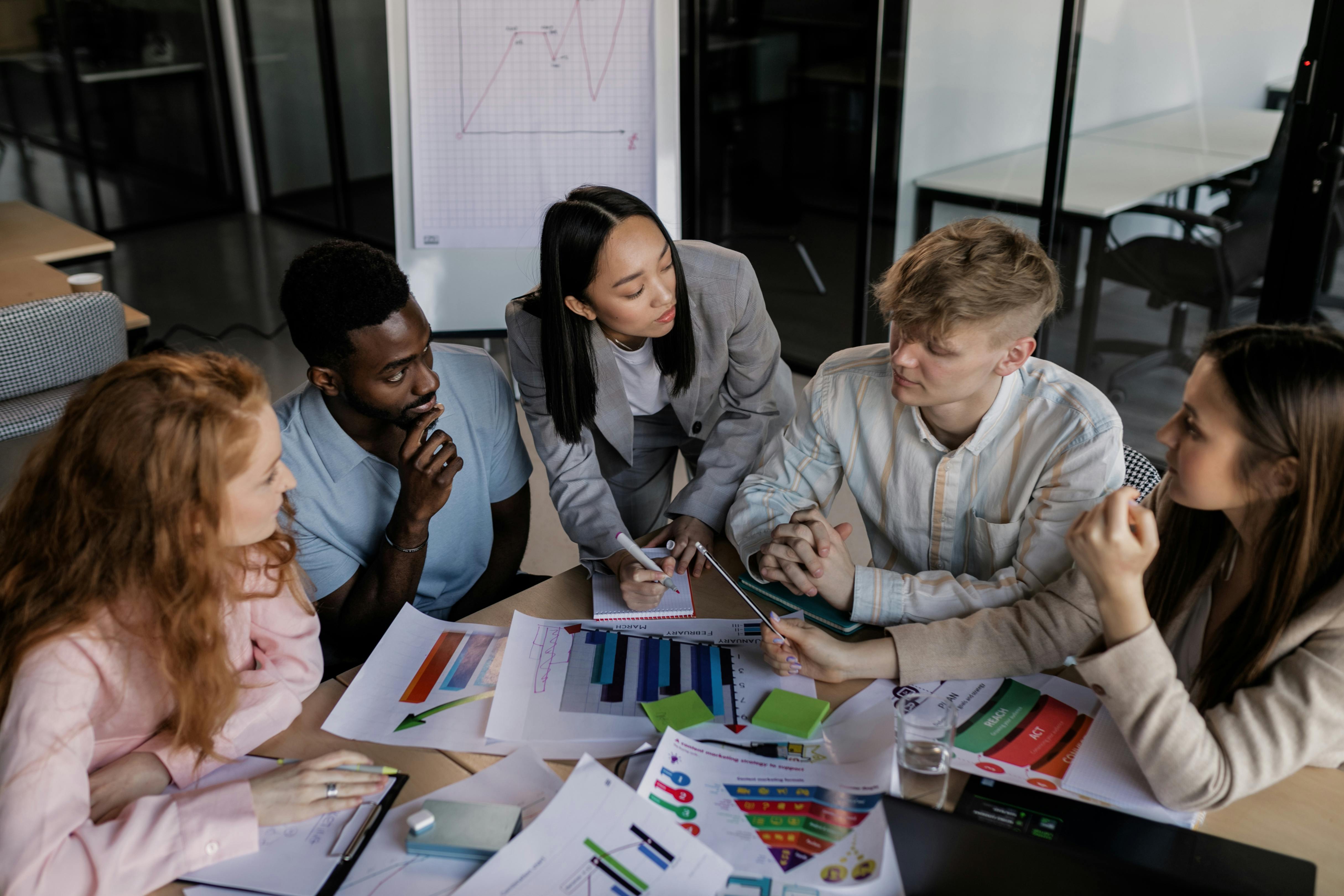 A diverse nonprofit team in a strategic meeting, analyzing data and collaborating on new grant proposals to find funding relief and avoid burnout.