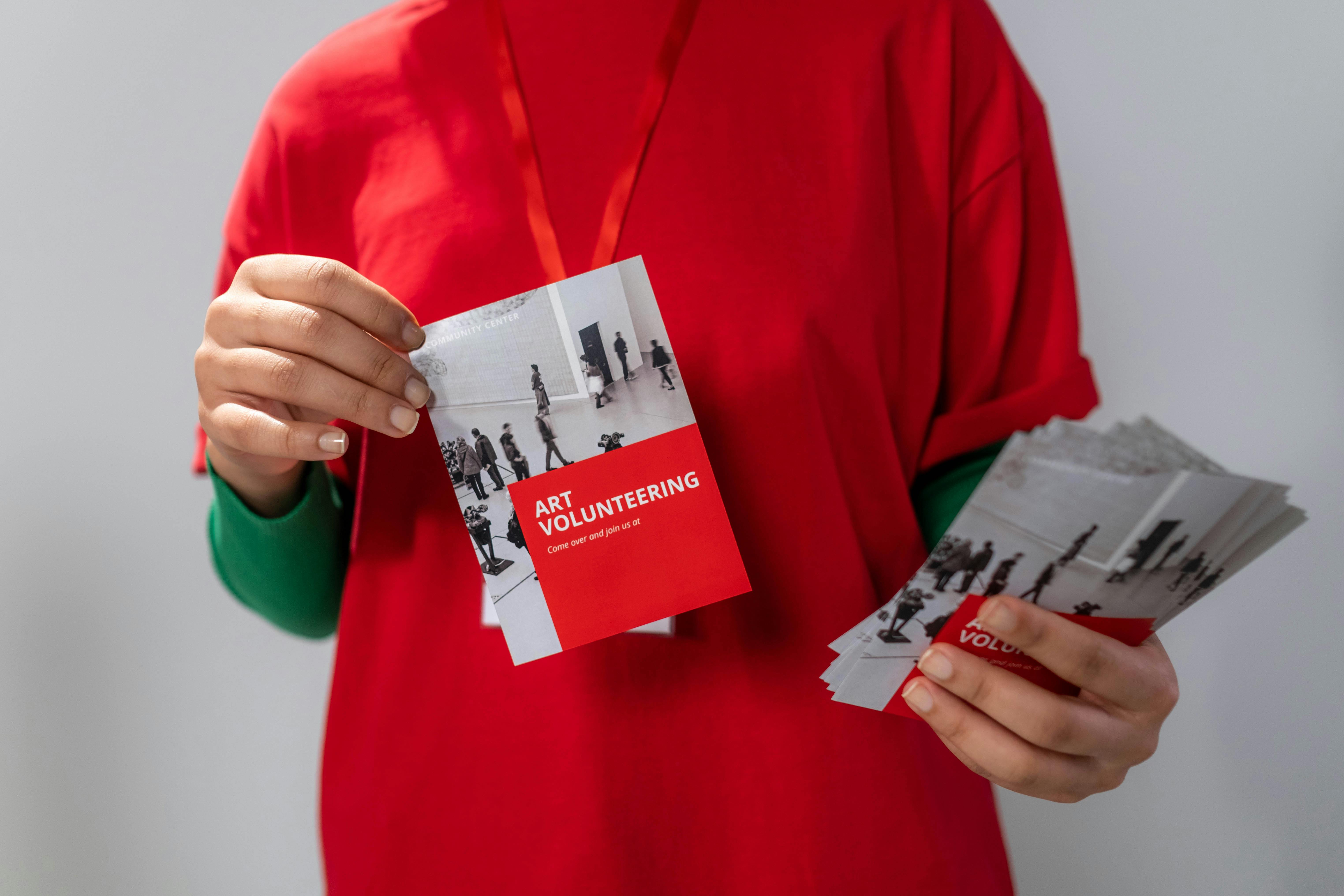 A person holds a flyer for "Art Volunteering," illustrating how 2025 fundraising letter templates can be adapted to request time and support, not just donations.