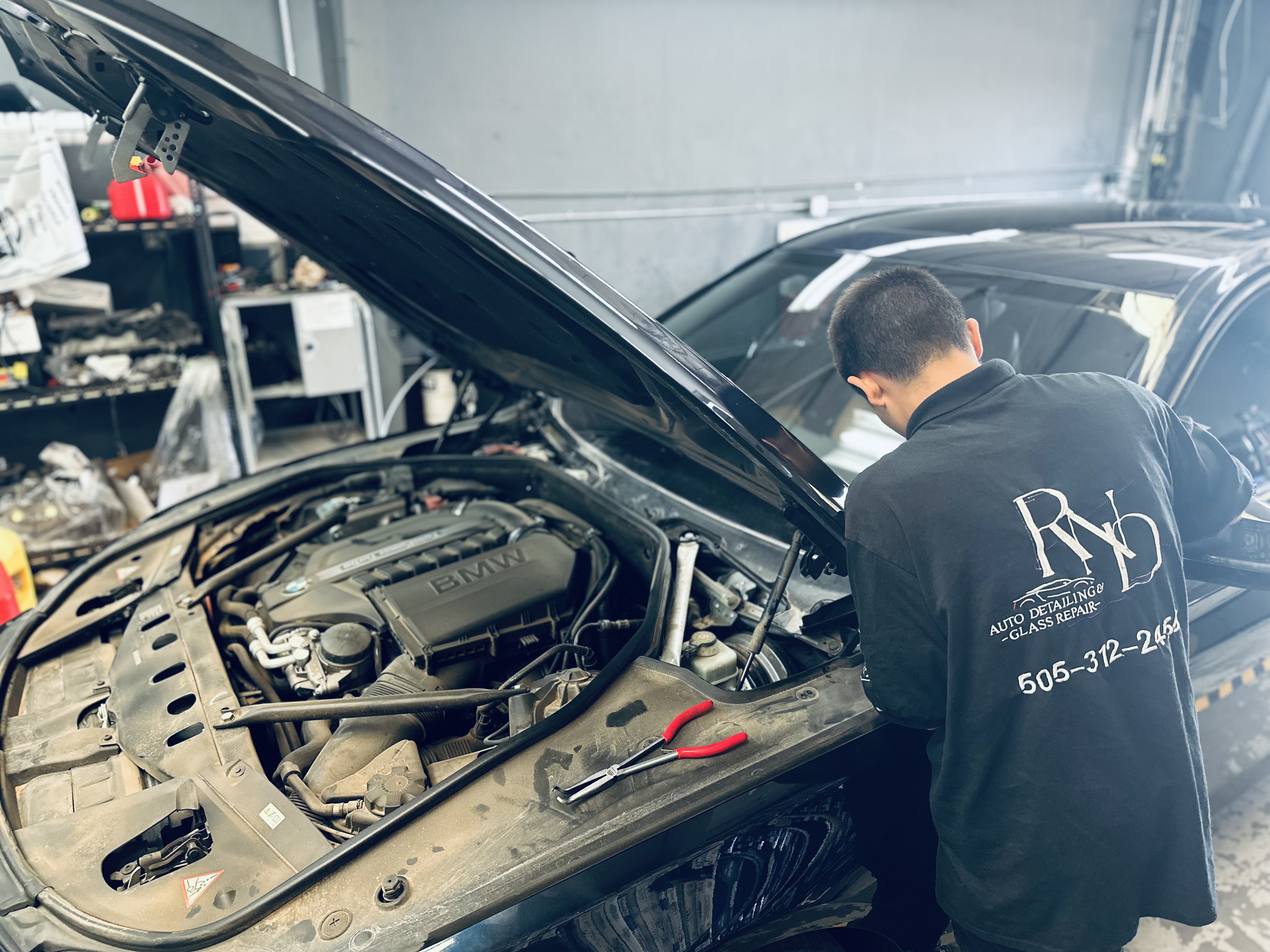 A certified technician closely examines a windshield chip and crack on a vehicle in the RND Auto Detailing shop, using a flashlight and inspection tools. A certified technician closely examines a windshield chip and crack on a vehicle in the RND Auto Detailing shop, using a flashlight and inspection tools.