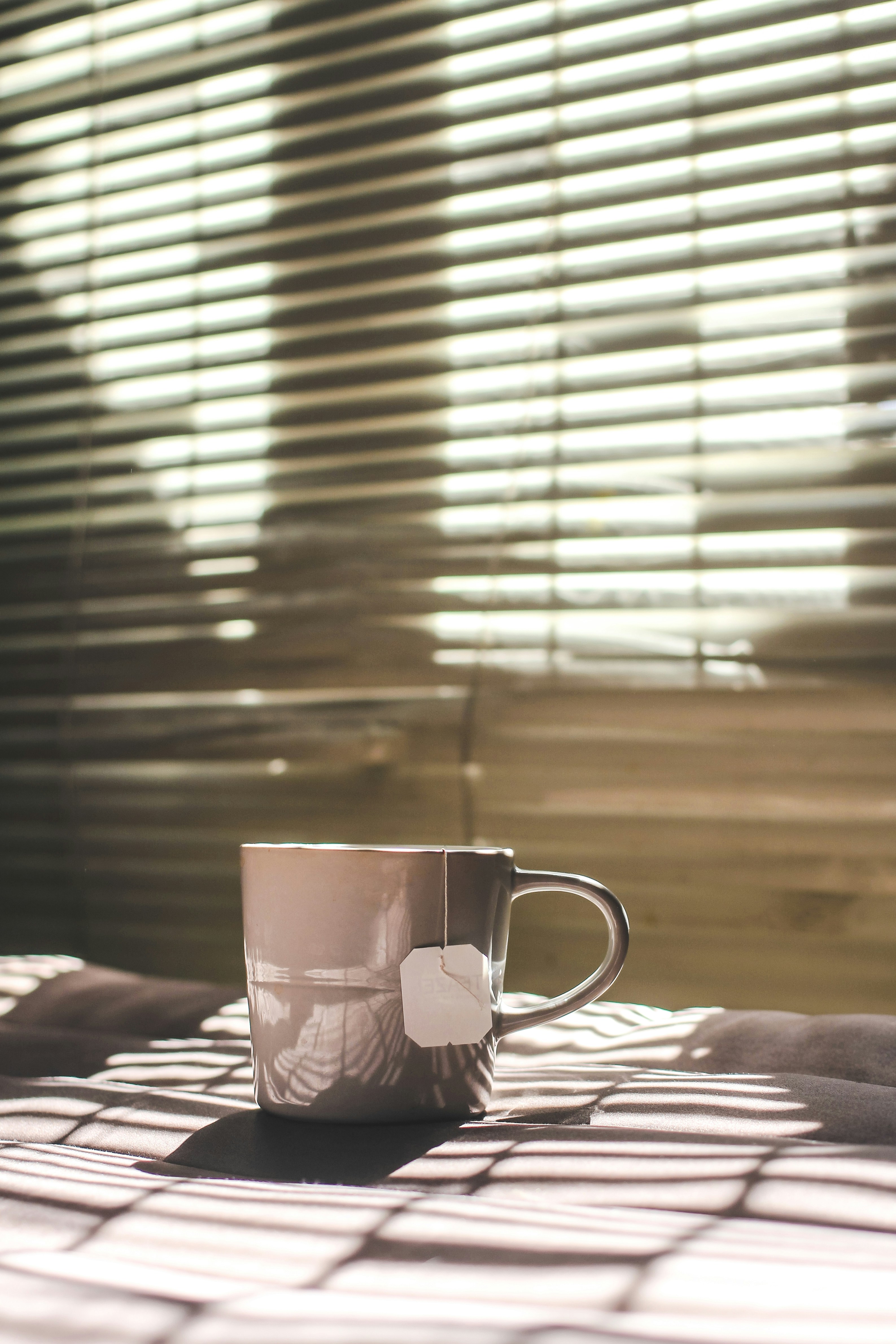 cup of coffee in front of mini blinds