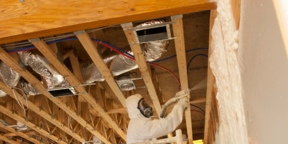 Contractor spraying spray foam insulation in wall